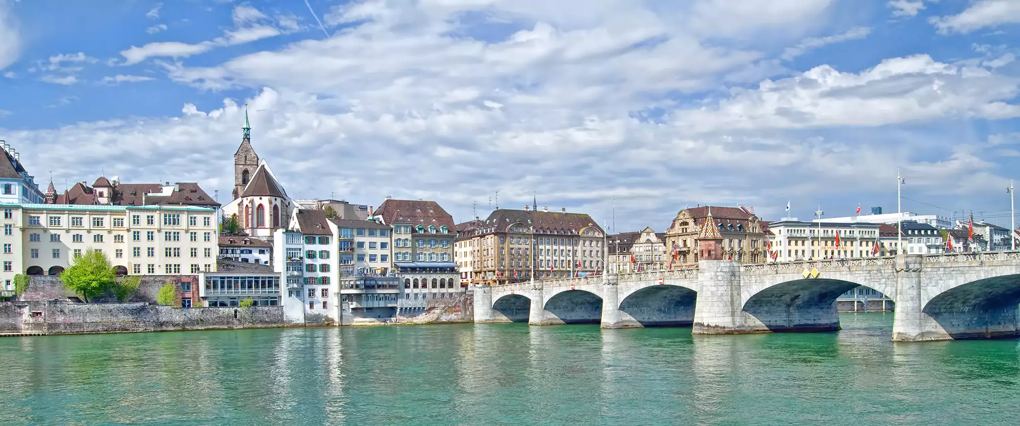 Mittlere Brücke in Basel - der Rhein schimmert türkis und am Himmel reisen Kumuluswolken