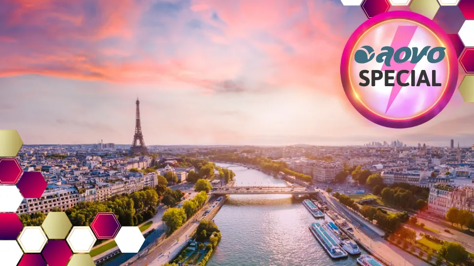 Panoramaansicht auf Paris bei Sonnenuntergang. Die untergehende Sonne erleuchtet die Stadt und Wolken in rosa Licht. Der Blick geht über den Fluss Seine, die Stadt erstreckt sich links und rechts. In der Ferne steht der Eifelturm.