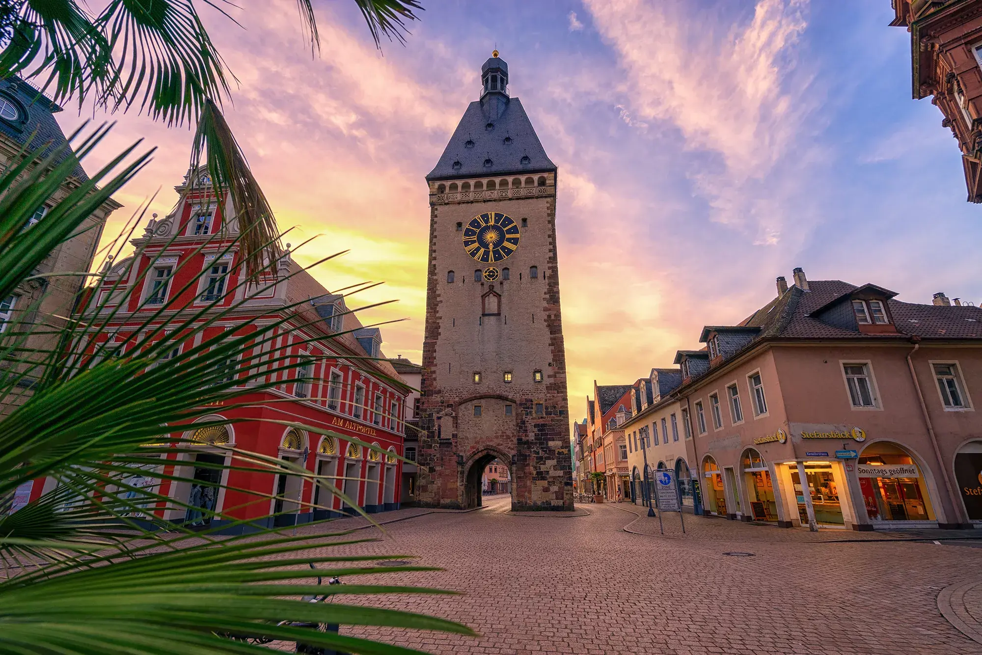 Blick auf das westliche Haupttor der Freien Reichsstadt Speyer- dem Altpörtel und Einkaufsstraße in der Abenddämmerung