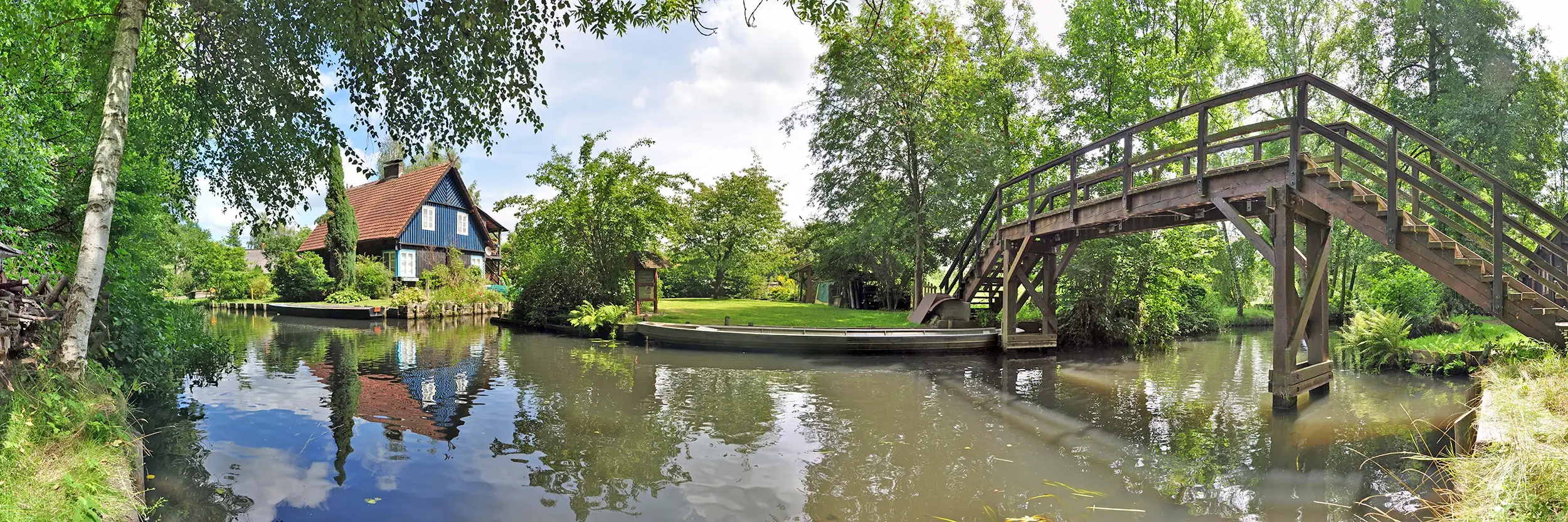typisches Haus am Fließ vor einer Holzbrücke im Spreewald