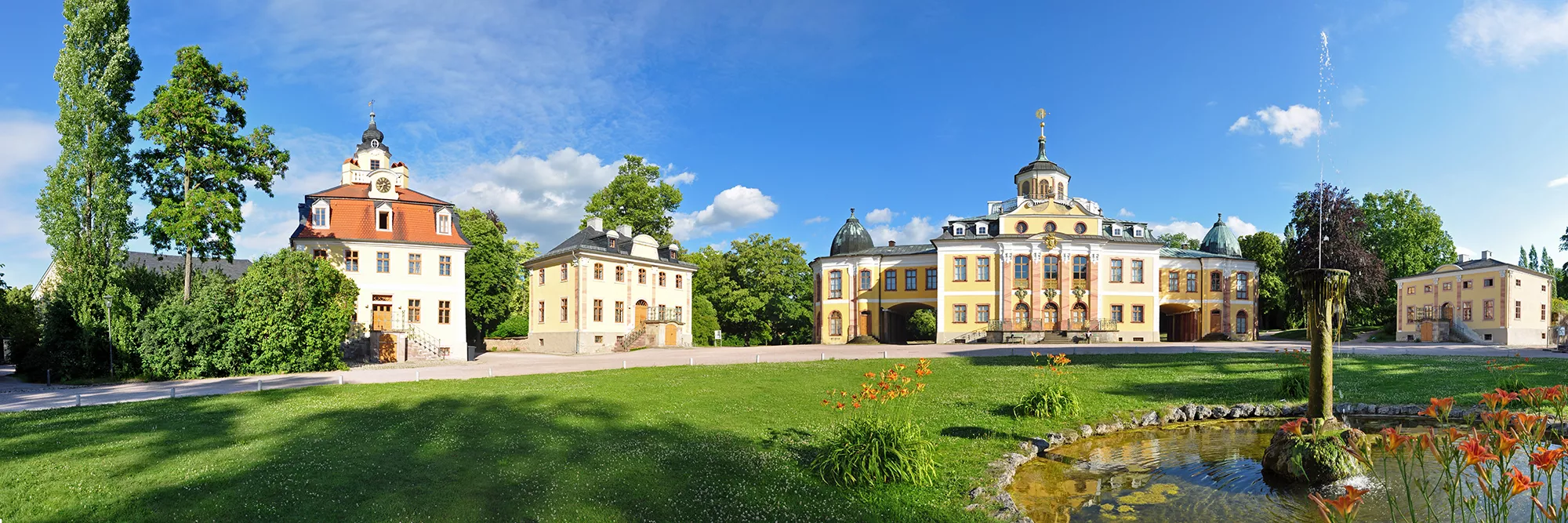 Panoramabild bei Sonnenschein vom Schloss Belvedere in Weimar mit Springbrunnen im Vordergrund.