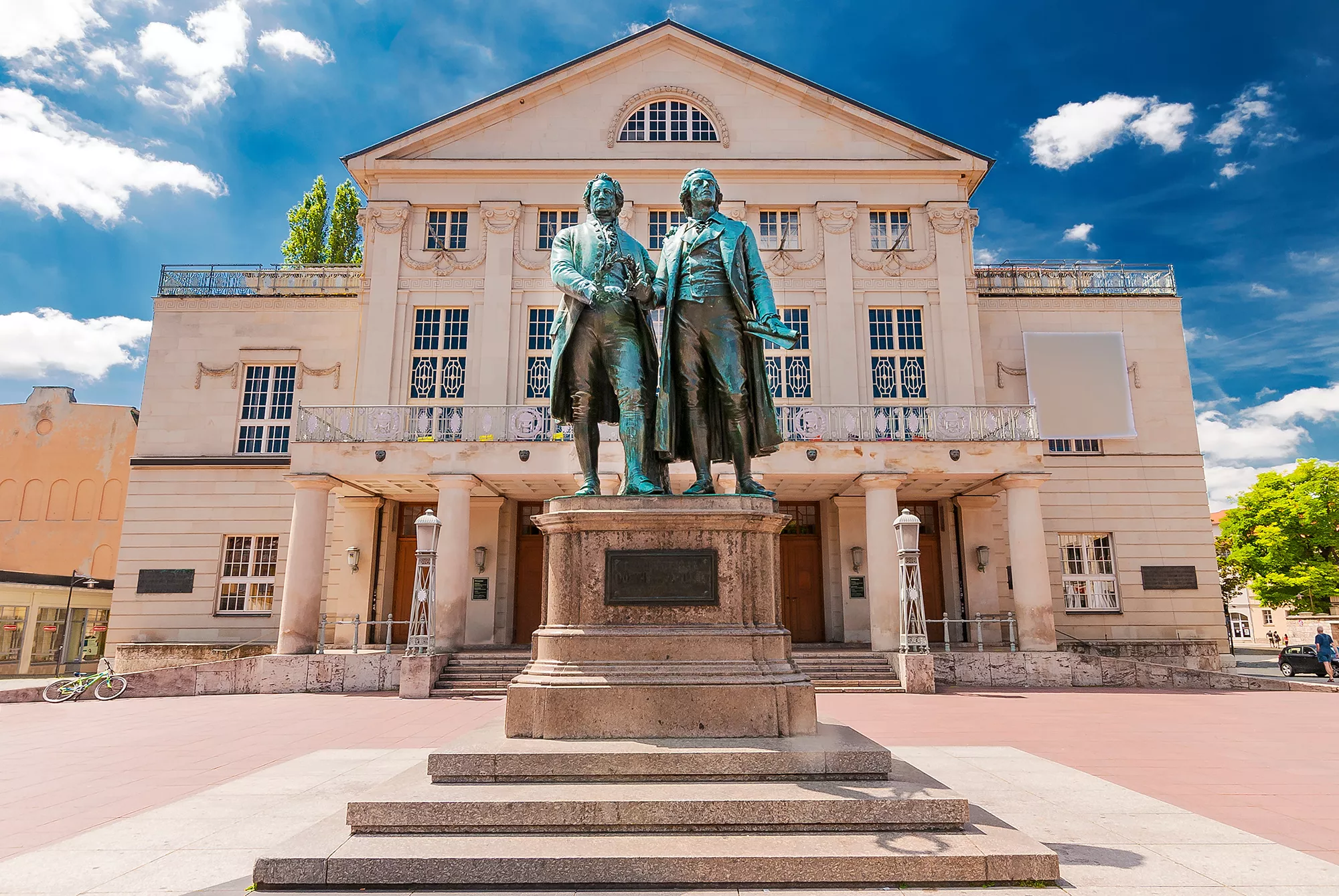 Goethe und Schiller Denkmal vor dem Theater der Stadt Weimar vor blauem Himmel mit Schäfchenwolken