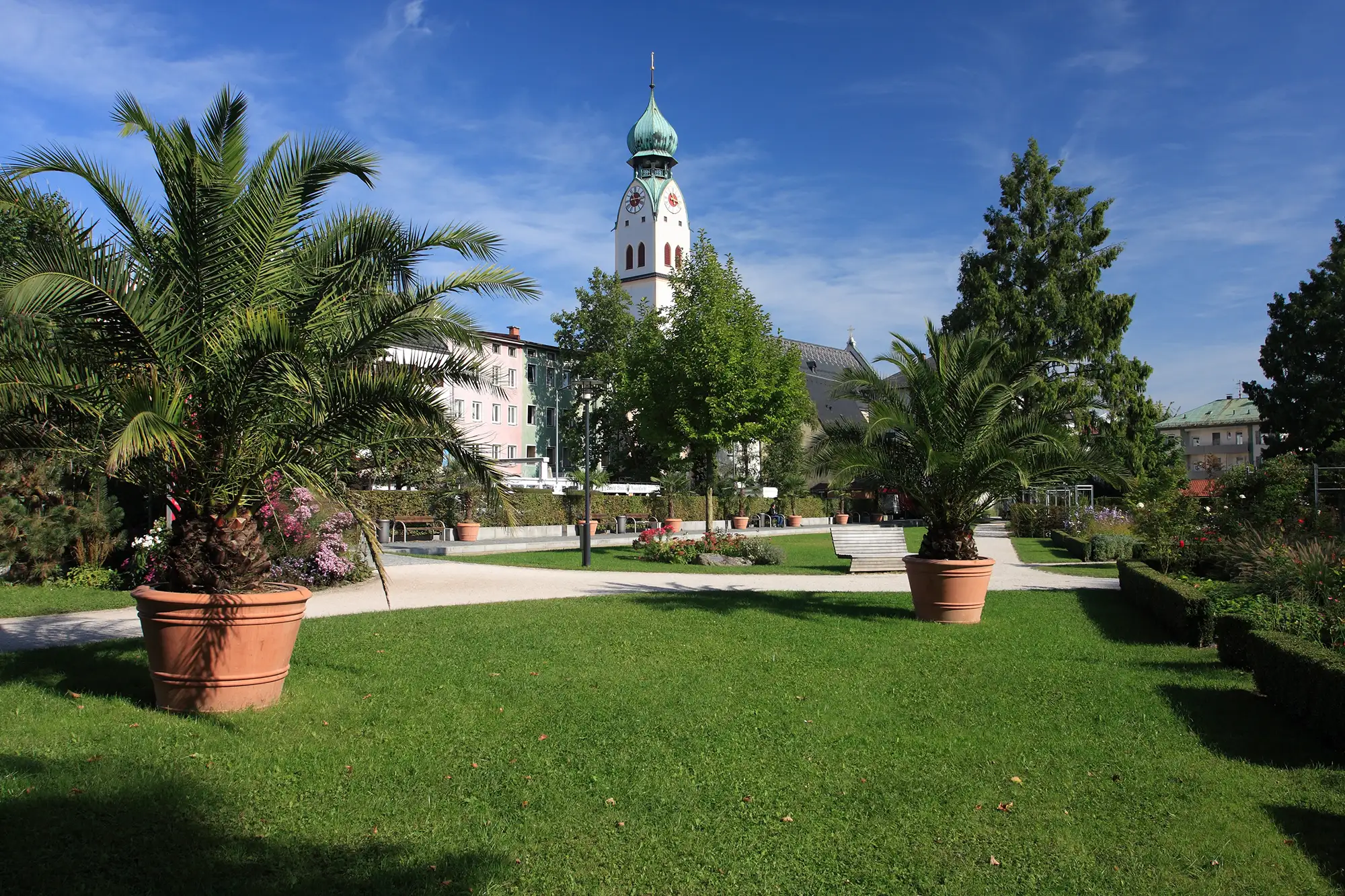 Blick auf die Sankt Nikolauskirche bei Sonnenschein vom Park aus bei einer Reise auf den Spuren der Rosenheim Cops