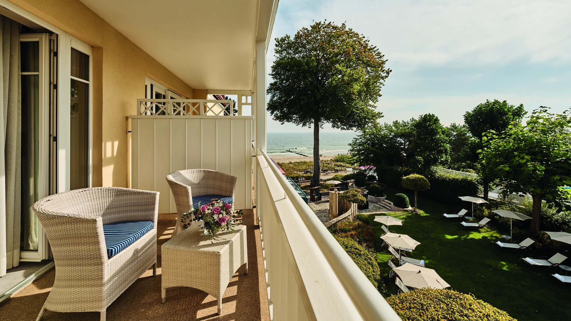 Eine einladende Balkonterrasse im aja Strandhotel Bansin mit gemütlichen Sitzmöbeln und direktem Blick auf die Ostsee. Genießen Sie entspannte Stunden mit dem Rauschen der Wellen und einer herrlichen Aussicht auf den Garten und das Meer – ein perfekter Ort für Erholung und Ruhe.