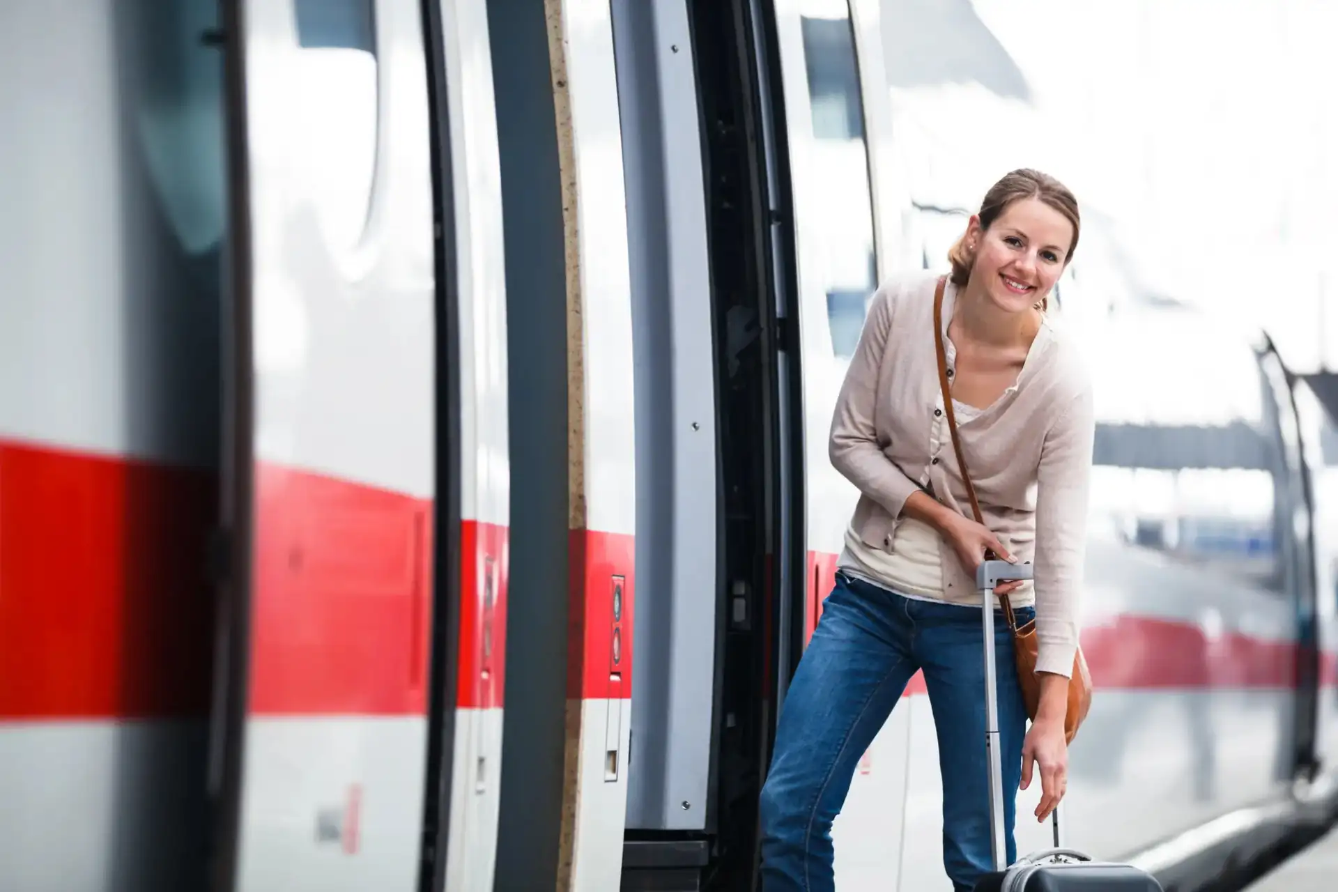 Bahnfahrt Symbolbild: Frau mit Koffer steigt am Bahnhof in den ICE ein (Kachelformat)