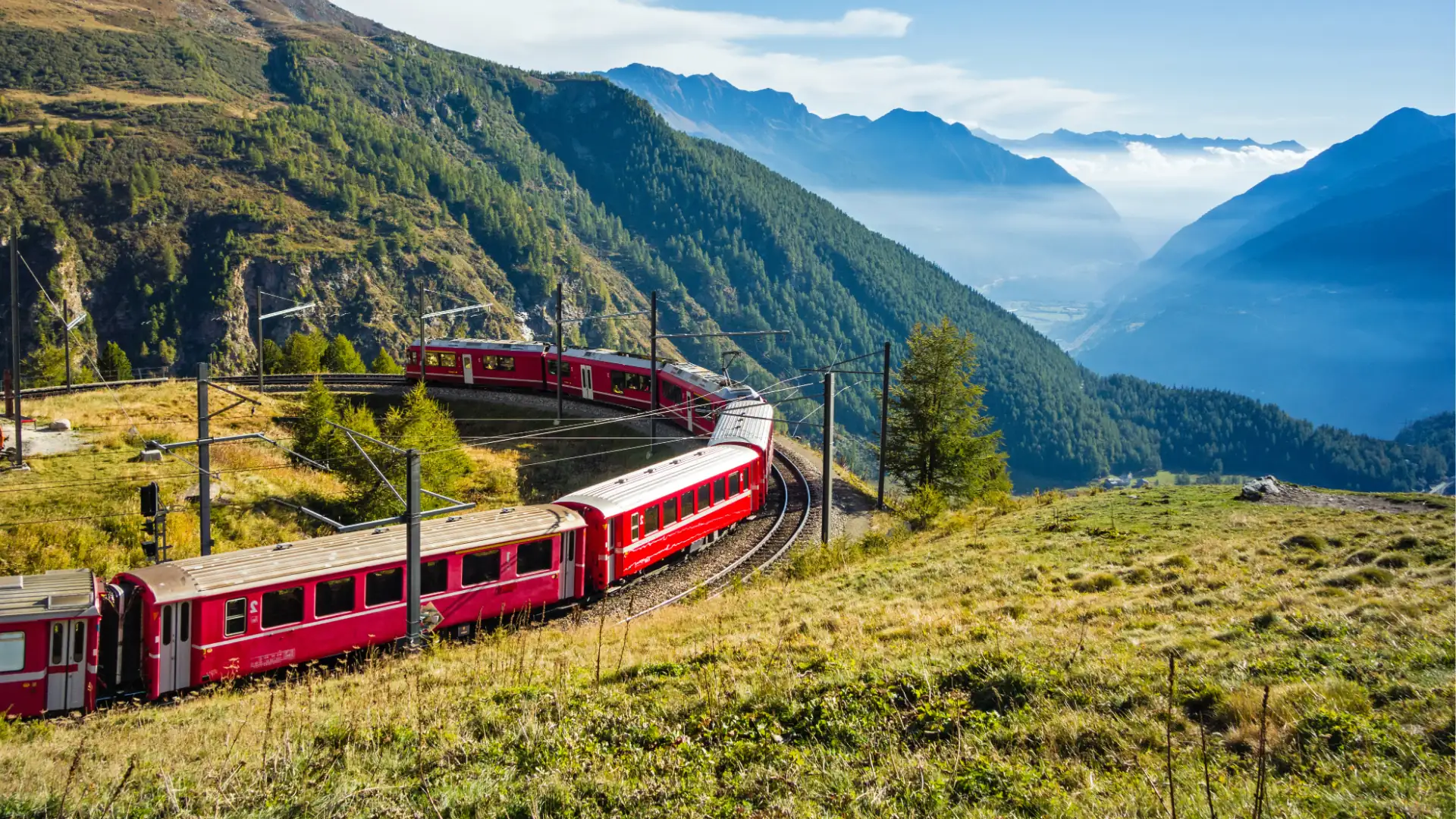 Bahnreisen Symbolbild: Roter Zug schlängelt sich durch eine beeindruckende Gebirgslandschaft.