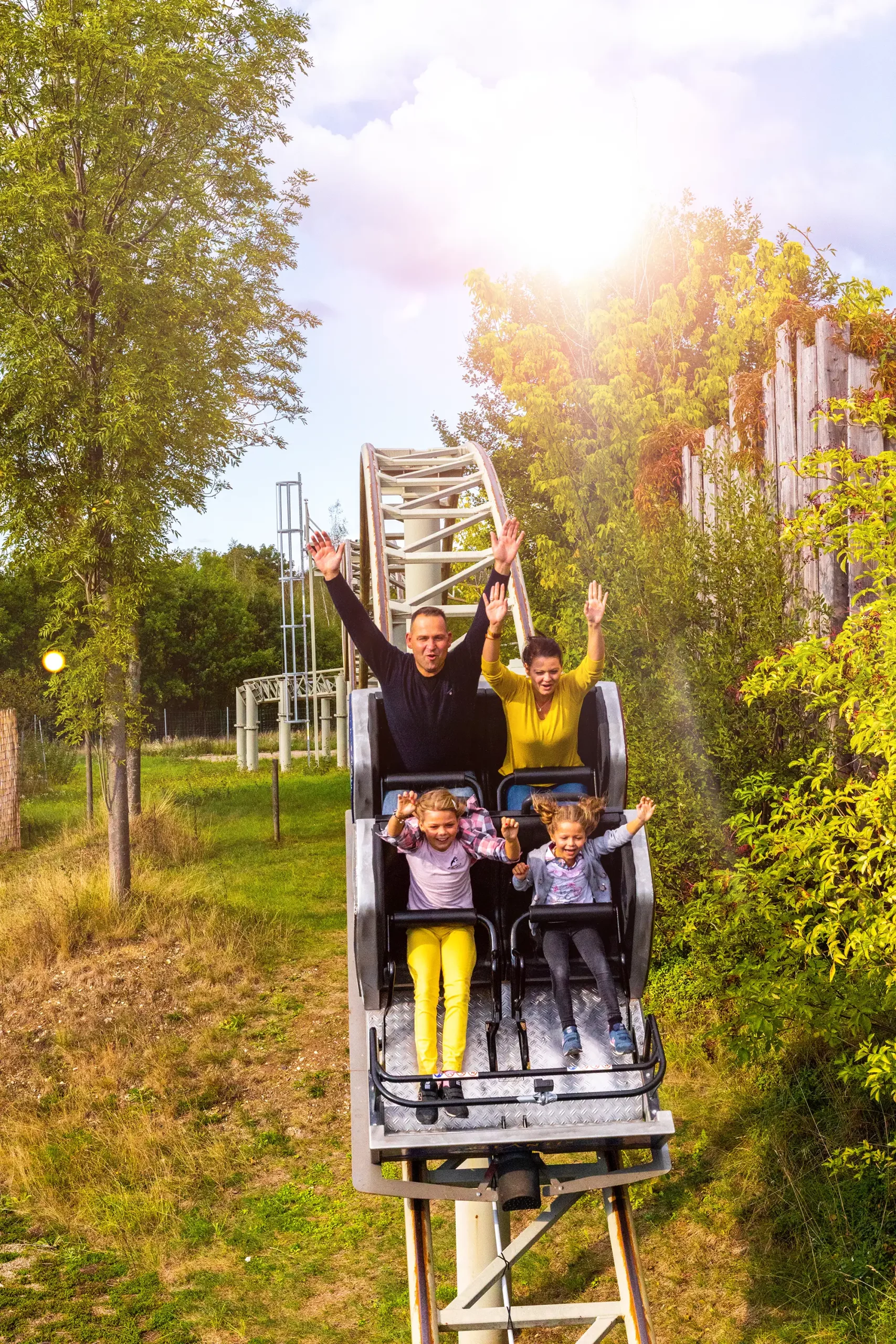 Belantis Leipzig - Drachenritt Achterbahn mit Familie im Achterbahnwagen die die Hände hochreißen
