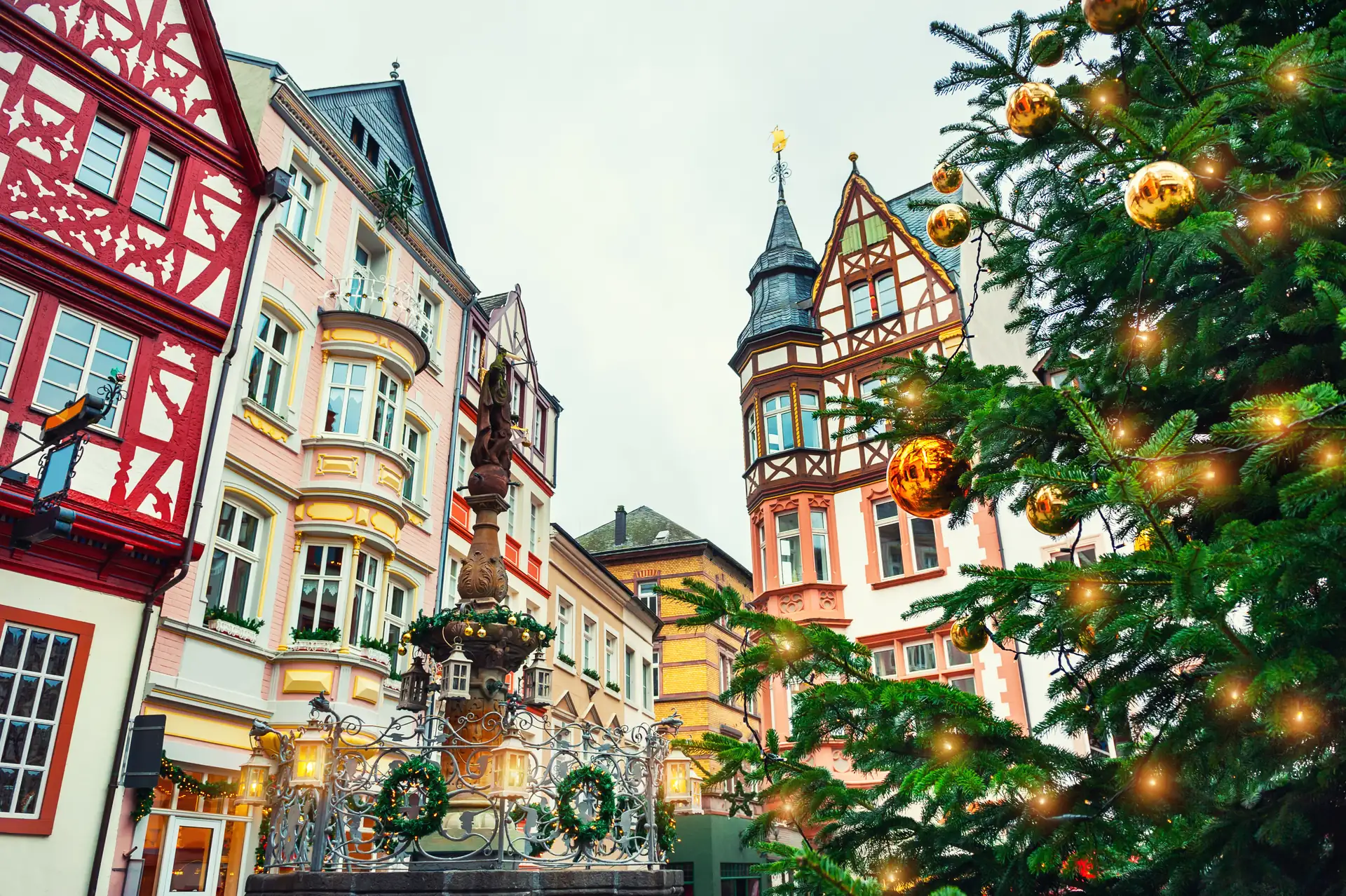 Weihnachtsbaum mit goldenen Kugeln auf dem Marktplatz in Bernkastel-Kues, umgeben von historischen Fachwerkhäusern und einem Brunnen