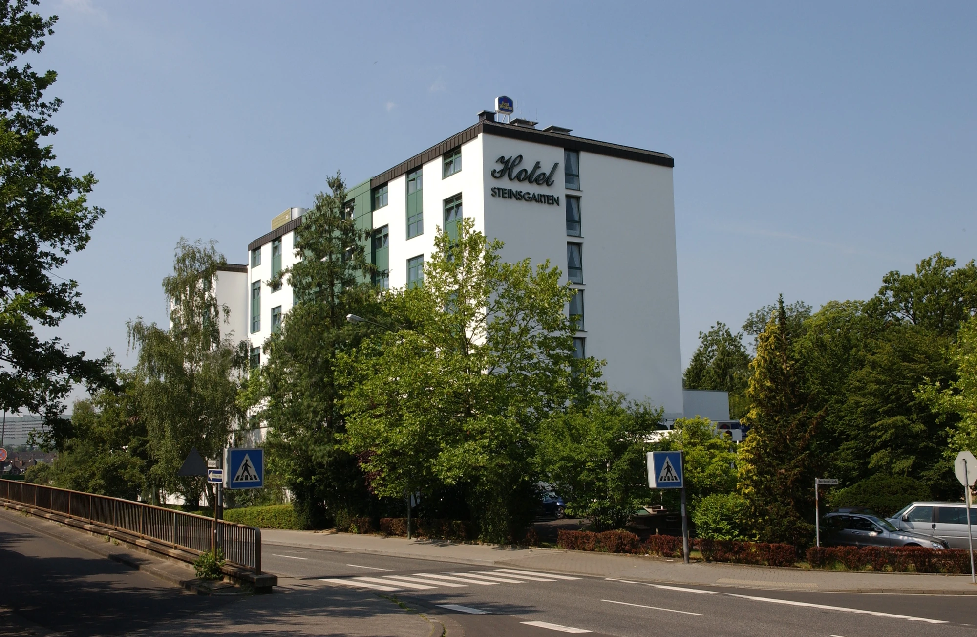 Außenansicht vom Best Western Plus Hotel Steinsgarten mit Bäumen und Straße im Vordergrund