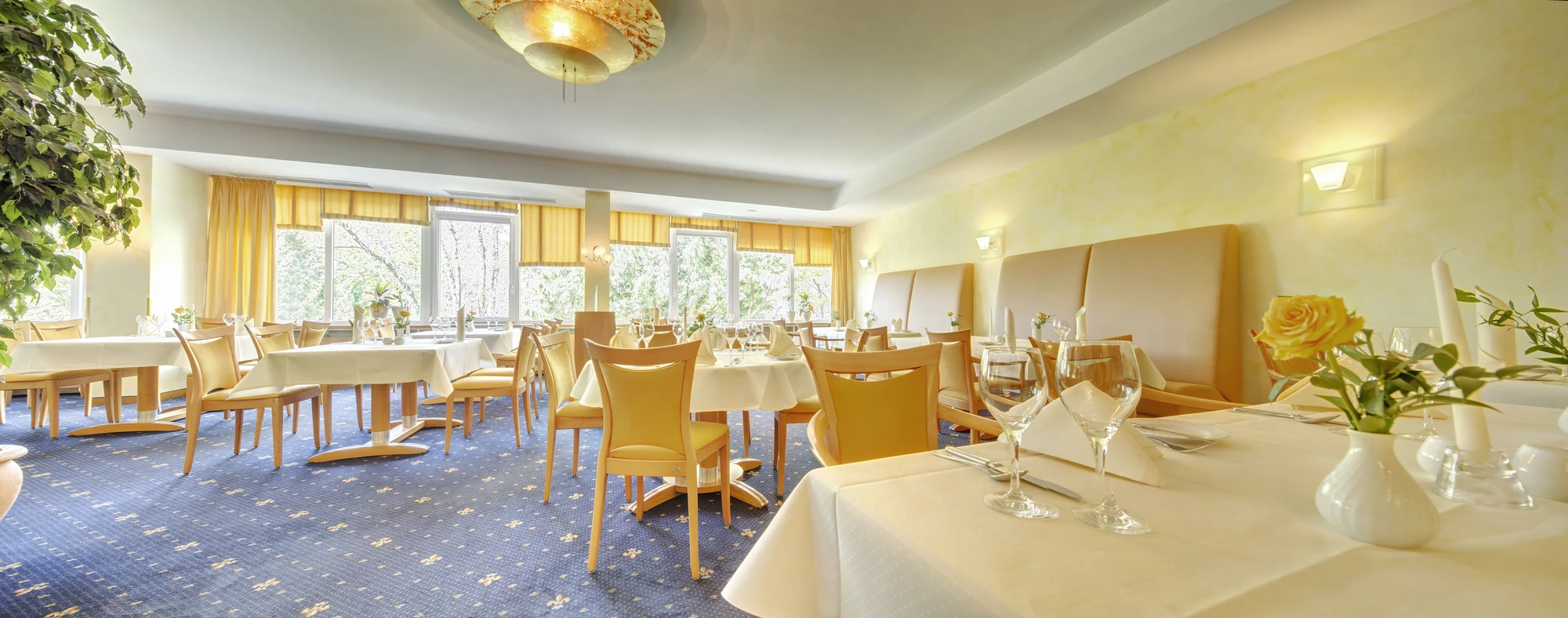 Restaurant im Best Western Plus Hotel Steinsgarten mit gedeckten Tischen mit Blumen und Pflanzen vor Fenstern