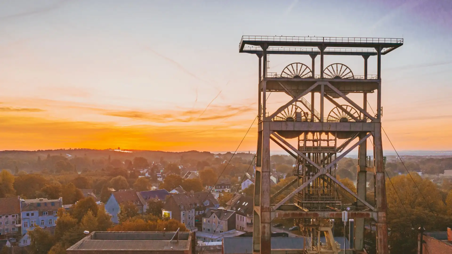 Historisches Fördergerüst im Sonnenuntergang über der Stadt