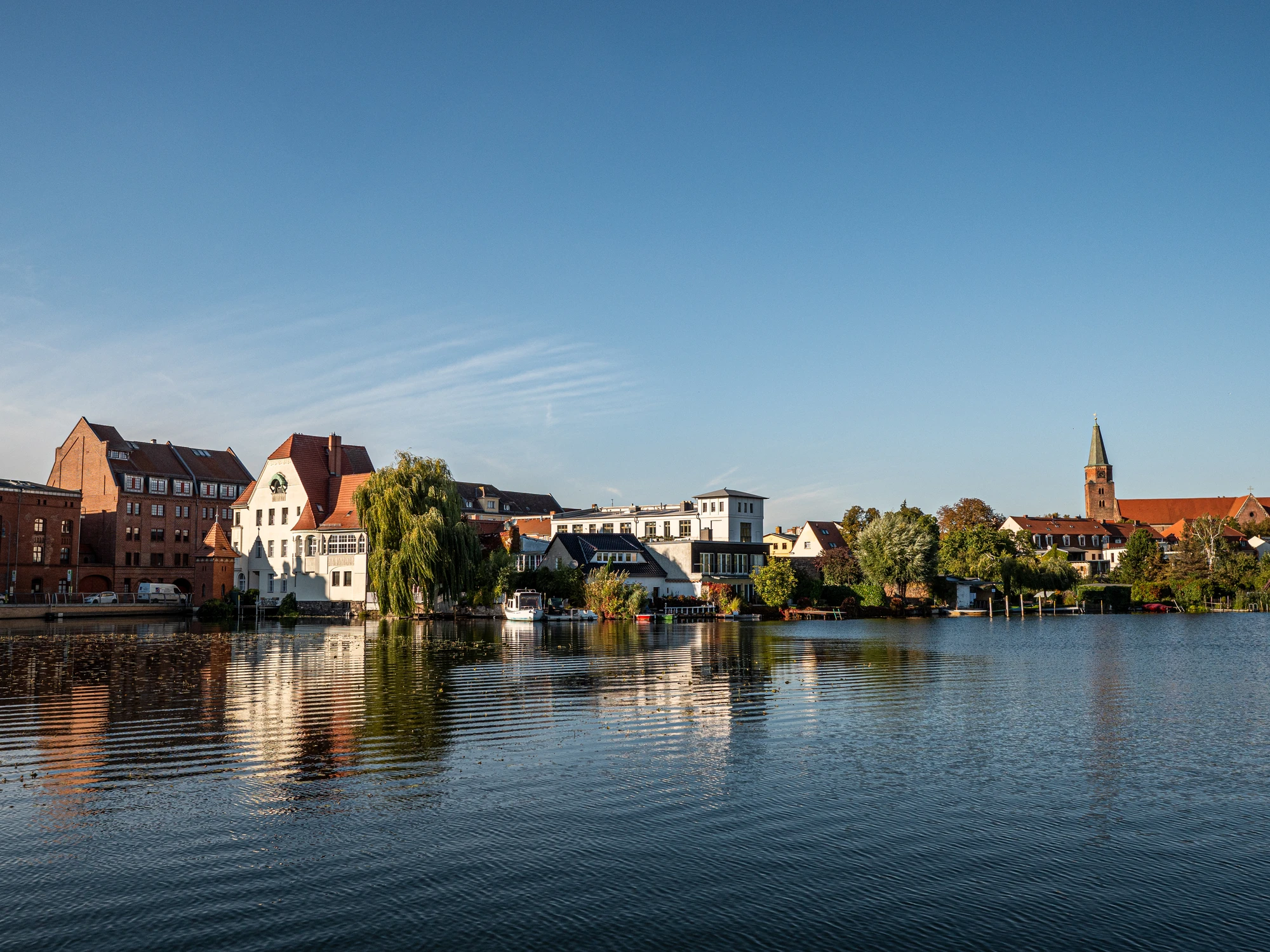Blick von der Havel aus an das Ufer von Brandenburg an der Havel mit Fachwerkhäusern und Gebäuden und der Dominsel mit Domturm im Hintergrun