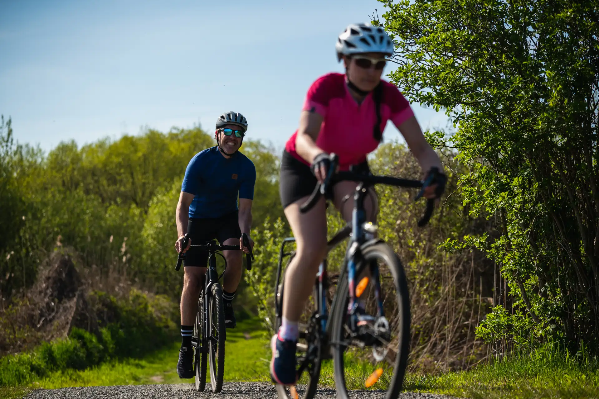 Zwei Personen fahren mit Gravelbikes auf einem Waldweg in Brandenburg, tragen Fahrradhelme und sportliche Kleidung