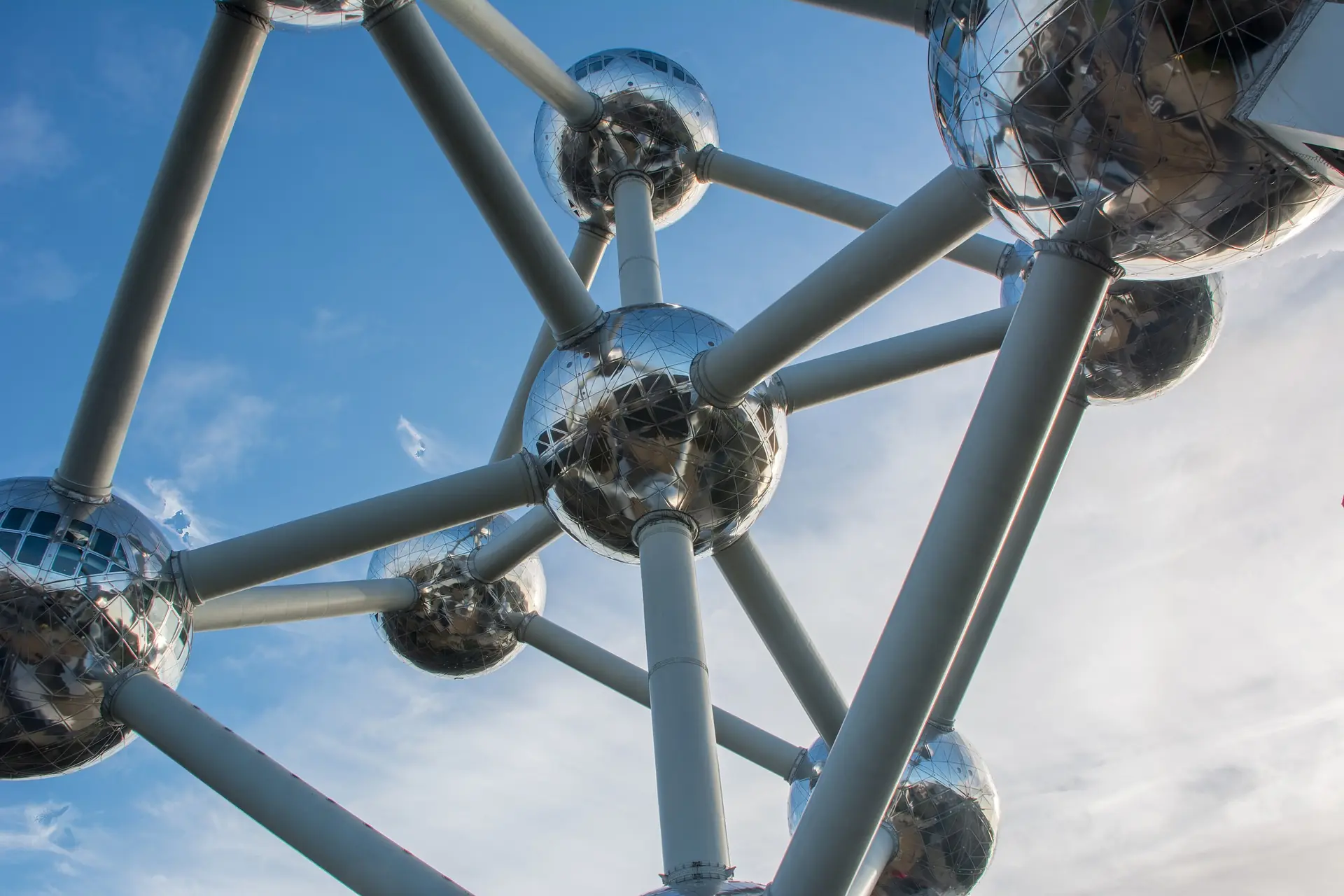 Nahaufnahme des Atomiums in Brüssel, das aus glänzendem Edelstahl besteht. Die charakteristischen Kugeln sind durch Röhren verbunden und strahlen futuristische Architektur aus.