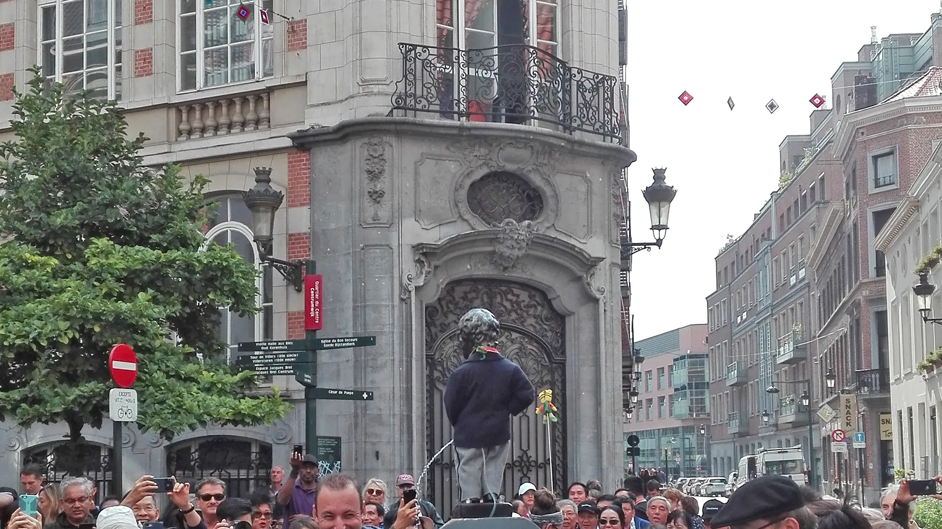 Manneken Pis wird in Kostüm durch die Menge getragen (in Brüssel)