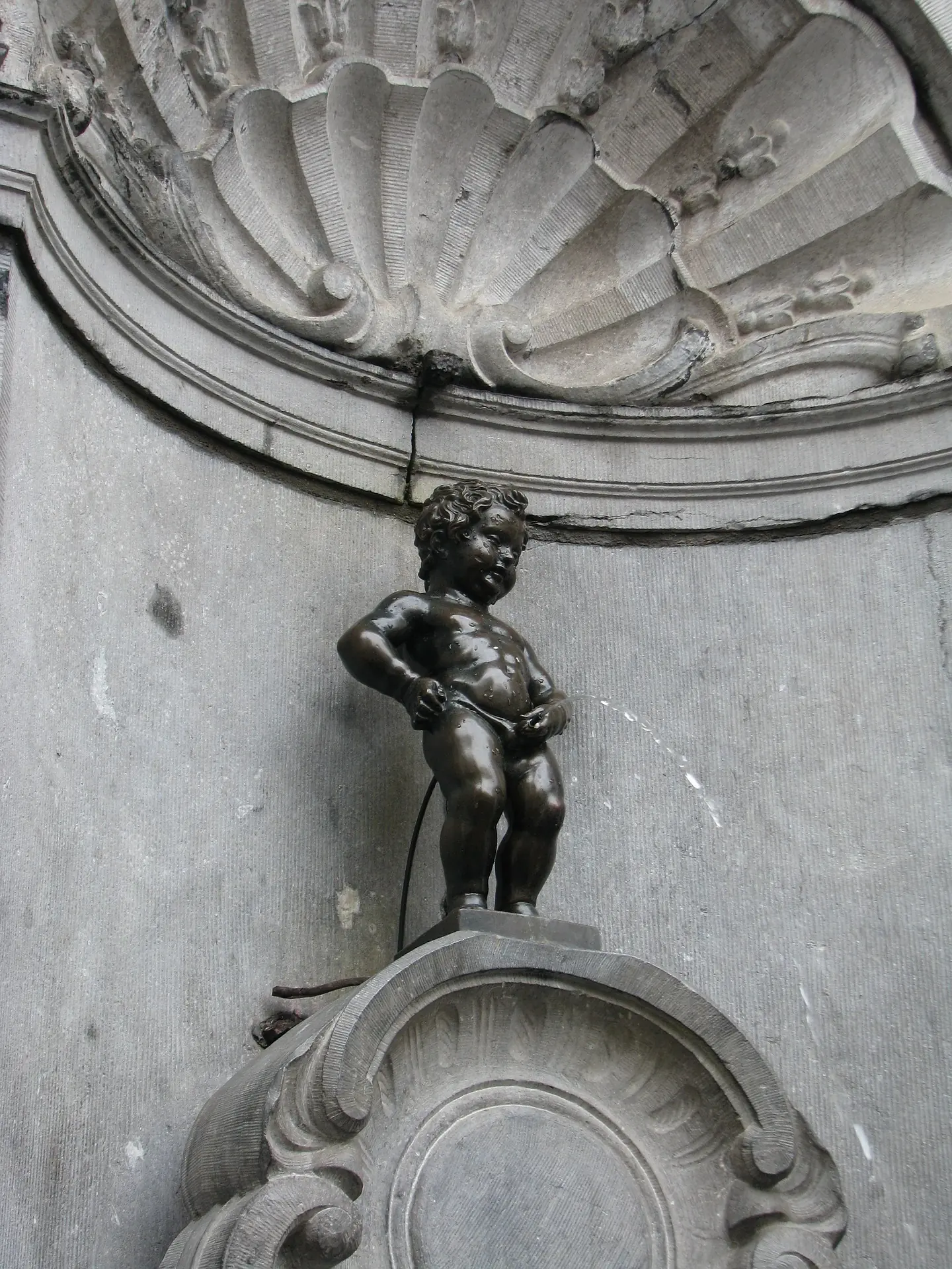 Die berühmte Bronzestatue Manneken Pis in Brüssel, die einen kleinen Jungen darstellt, der in einen Brunnen uriniert. Die Statue ist ein beliebtes Wahrzeichen der Stadt.