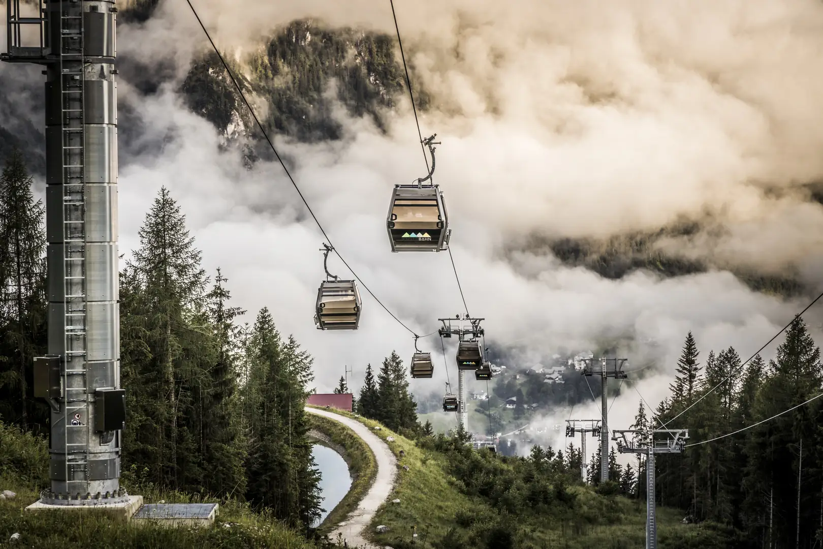 Seilbahn vor wolkenverhangenen Felsmassiv