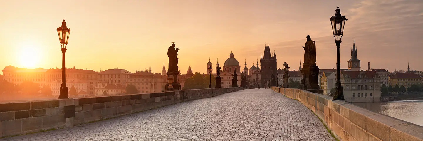 Stadtansicht von Prag mit Karlsbrücke, Barockstatuen und Laternen in Richtung Altstadt bei Sonnenaufgang