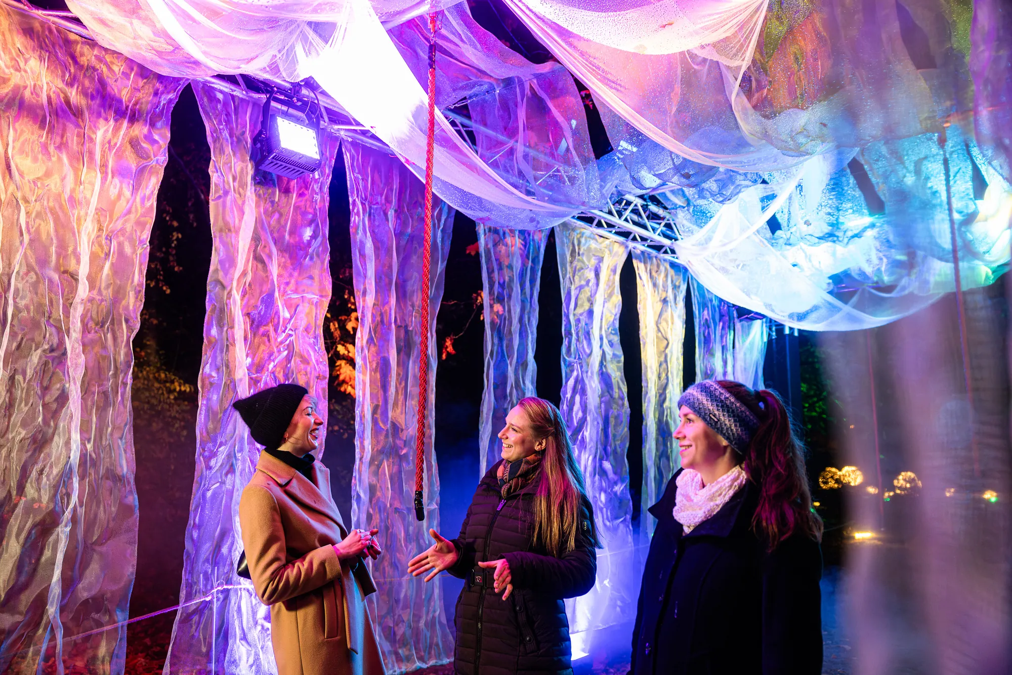 Christmas Garden 2023 - Dresden - Wolkentunnel,, bunte leuchte Wolkentücher, Menschen darunter und reden fröhlich