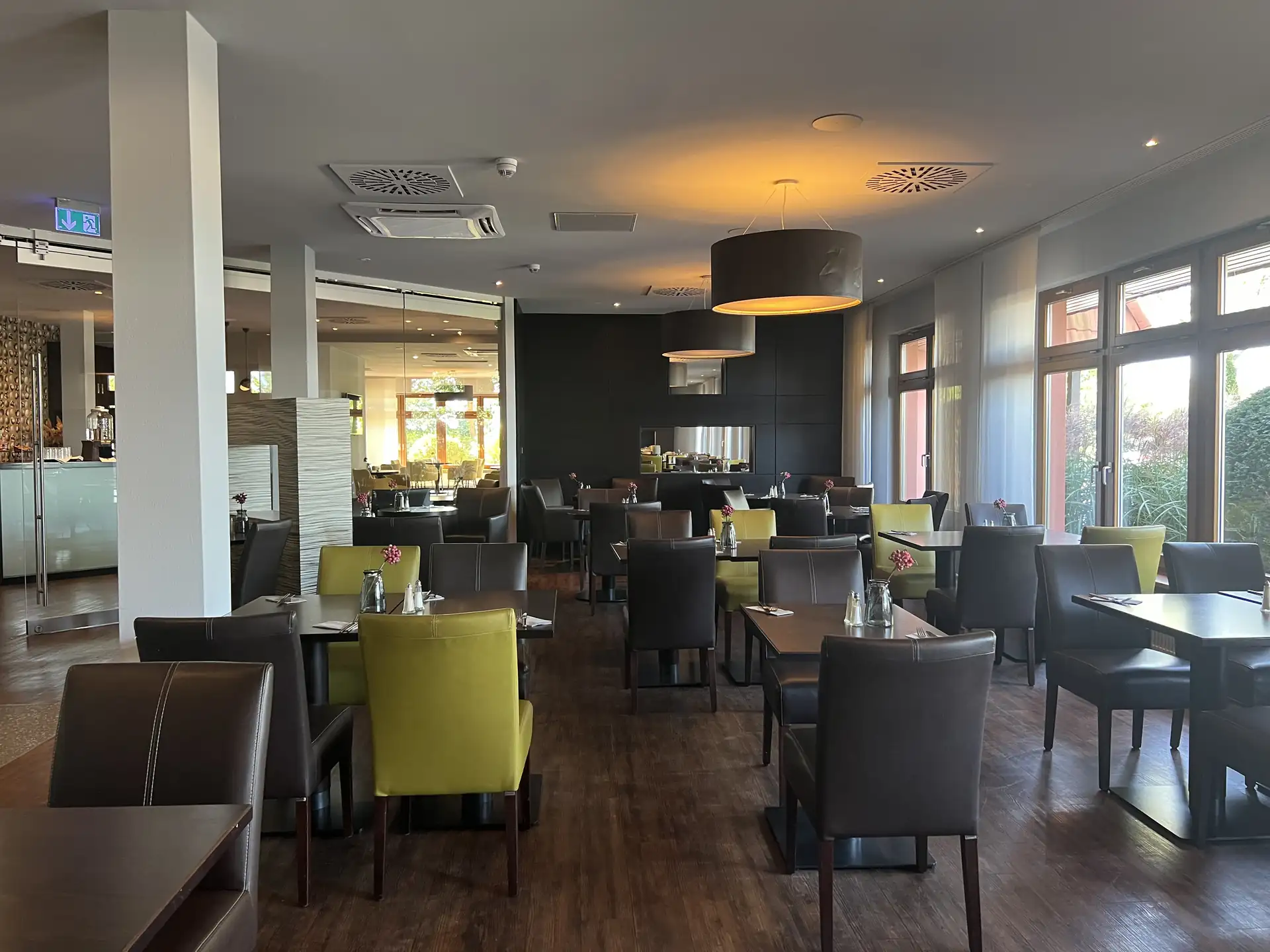 Modern eingerichteter Speiseraum im Classik Hotel Magdeburg mit dunklen und einigen grünen Stühlen, Holzboden und großen Fenstern