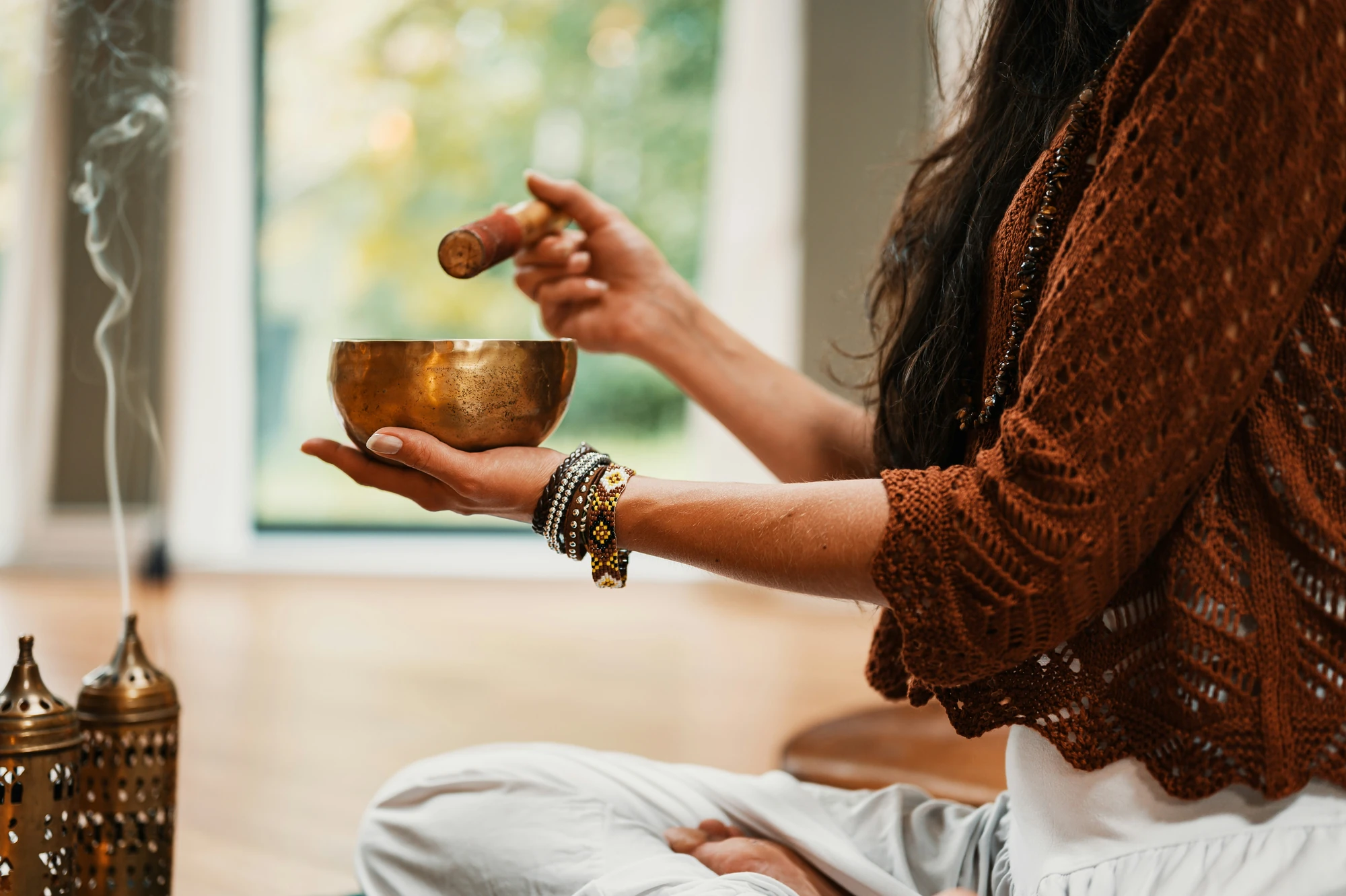 Frau im braunen Strickpullover mit goldener Klangschale im Wellnessurlaub