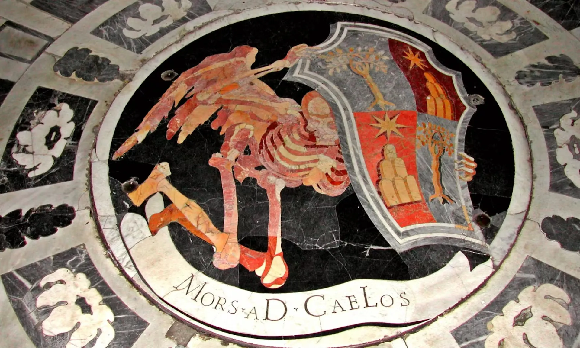 Das Bild zeigt ein kunstvoll gestaltetes Mosaik mit der Inschrift 