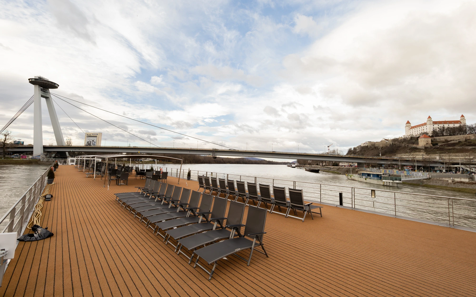 Schwarze Liegestühle in einer Reihe mit Blick auf das Ufer und den Fluss auf dem Sonnendeck der DCS Amethyst 1