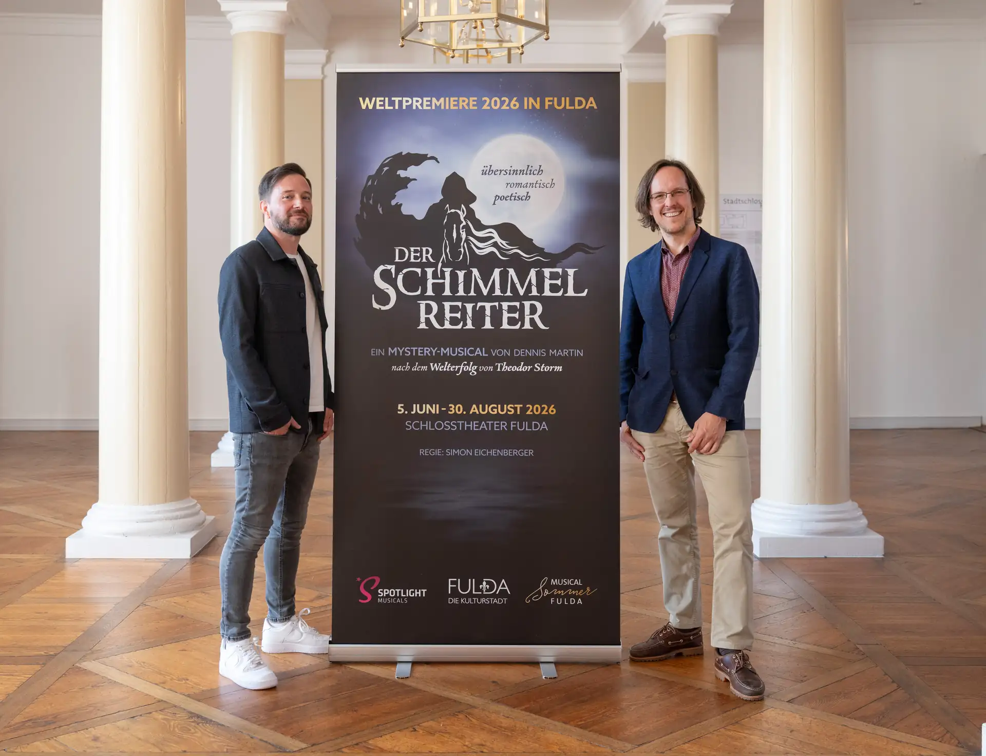 Pressekonferenz zum Musical Der Schimmelreiter: D. Martin und P. Scholz stehen neben einem Banner für das Musical 