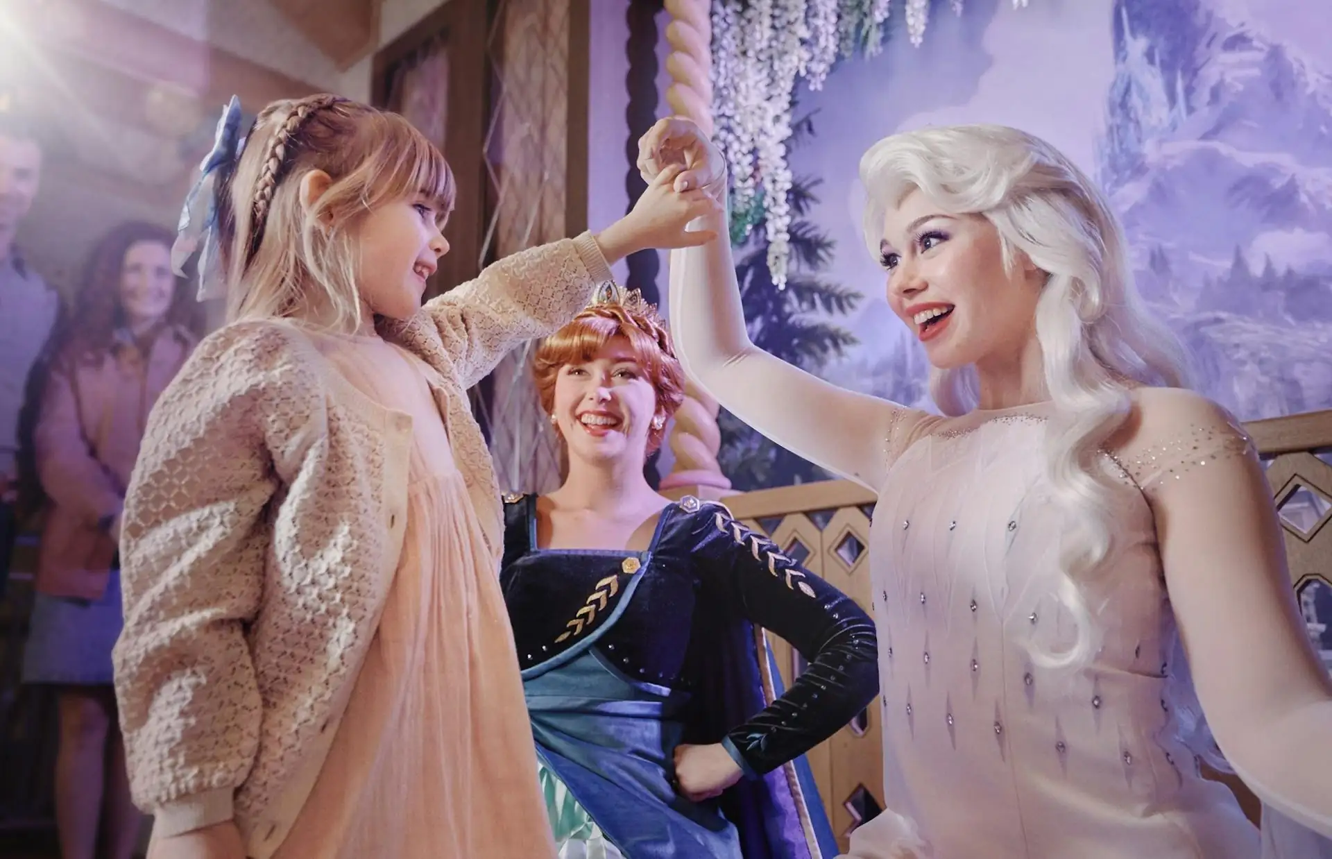 Drei Personen in Disneyland Paris, zwei als Anna und Elsa aus 