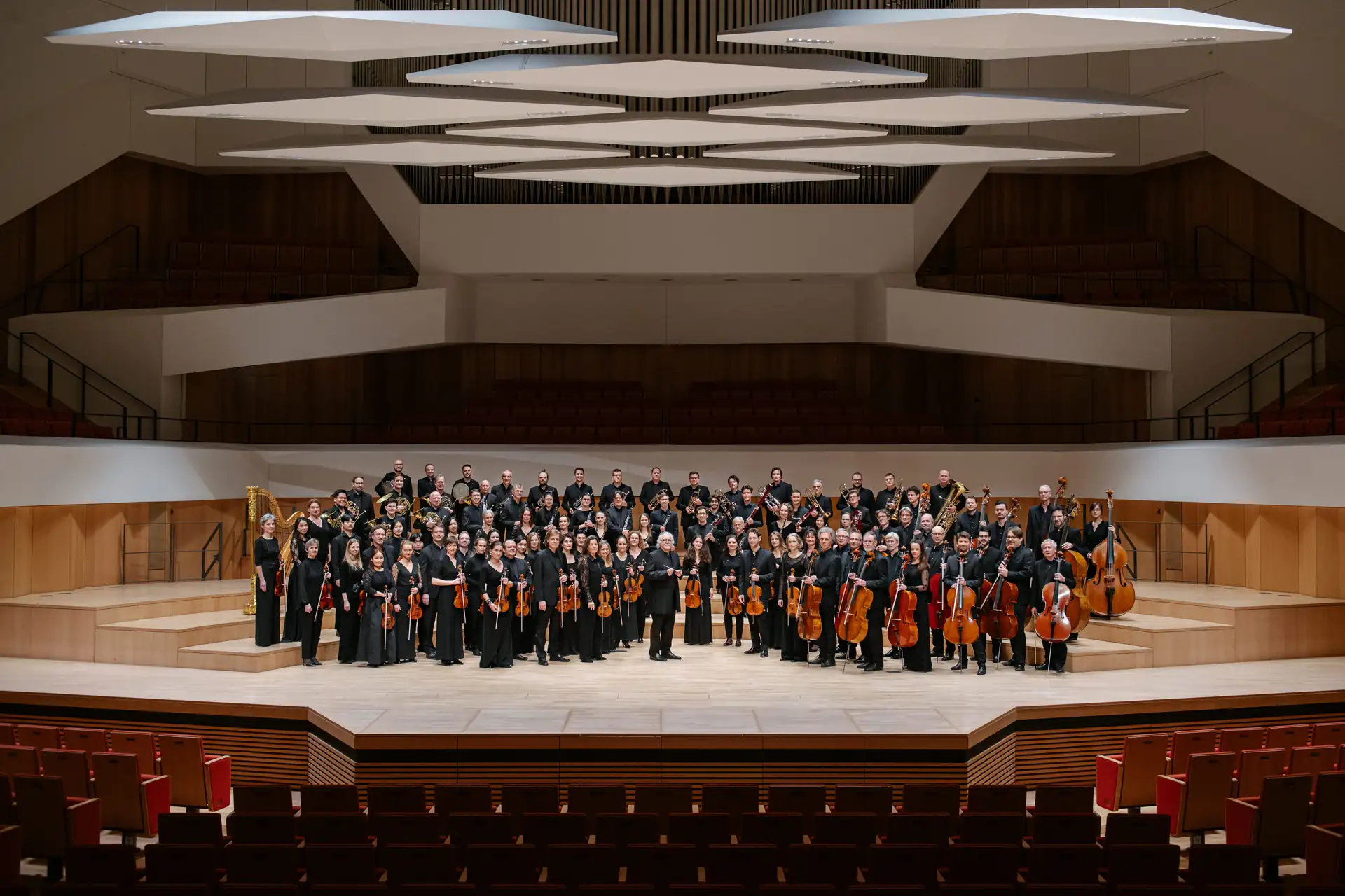 Dresdner Philharmonie Orchester mit Musikern in schwarzer Konzertkleidung auf Bühne eines modernen Konzertsaals