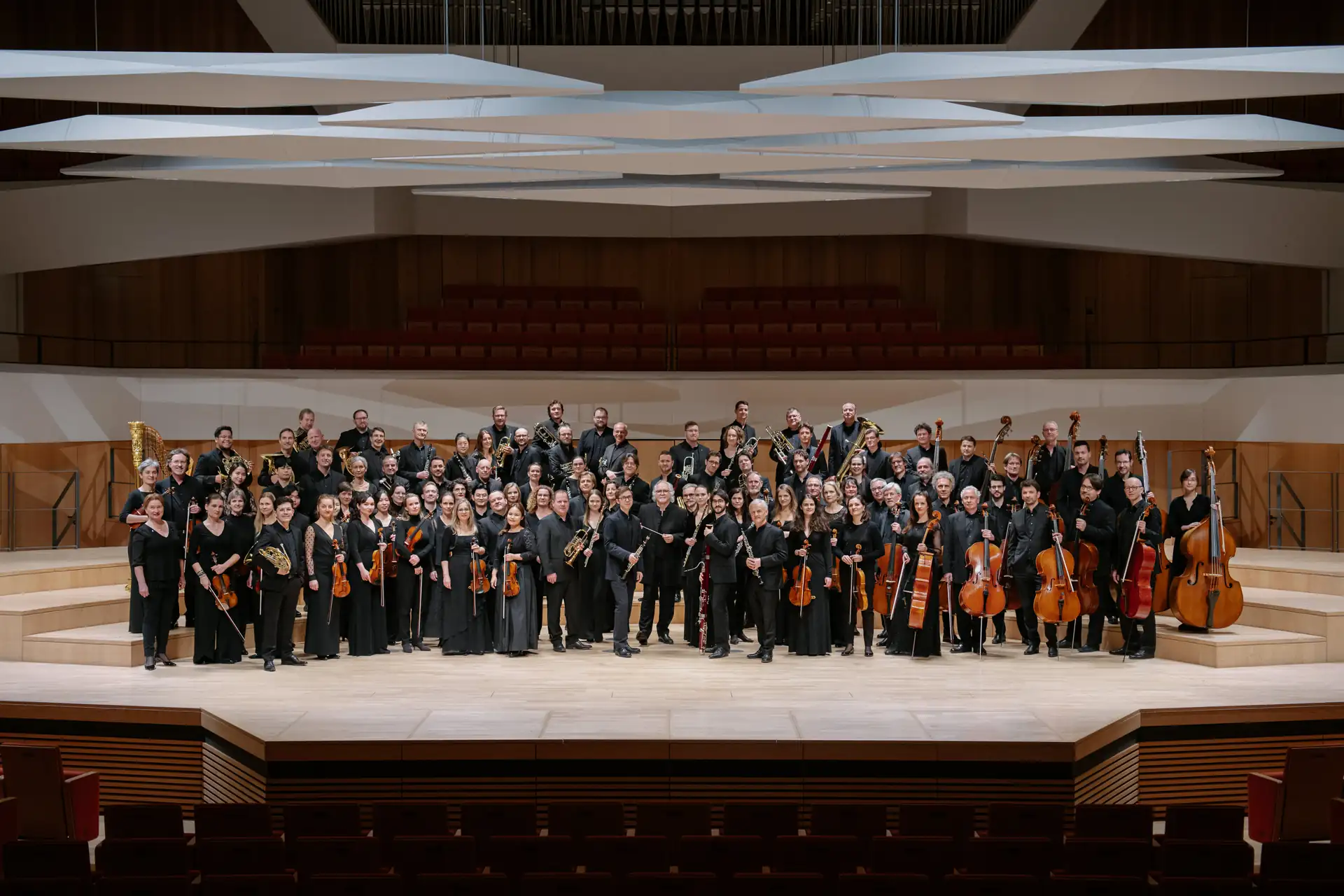 Das Dresdner Philharmonie Orchester 2024 steht auf der Bühne eines Konzertsaals mit ihren Instrumenten in schwarzer Konzertkleidung