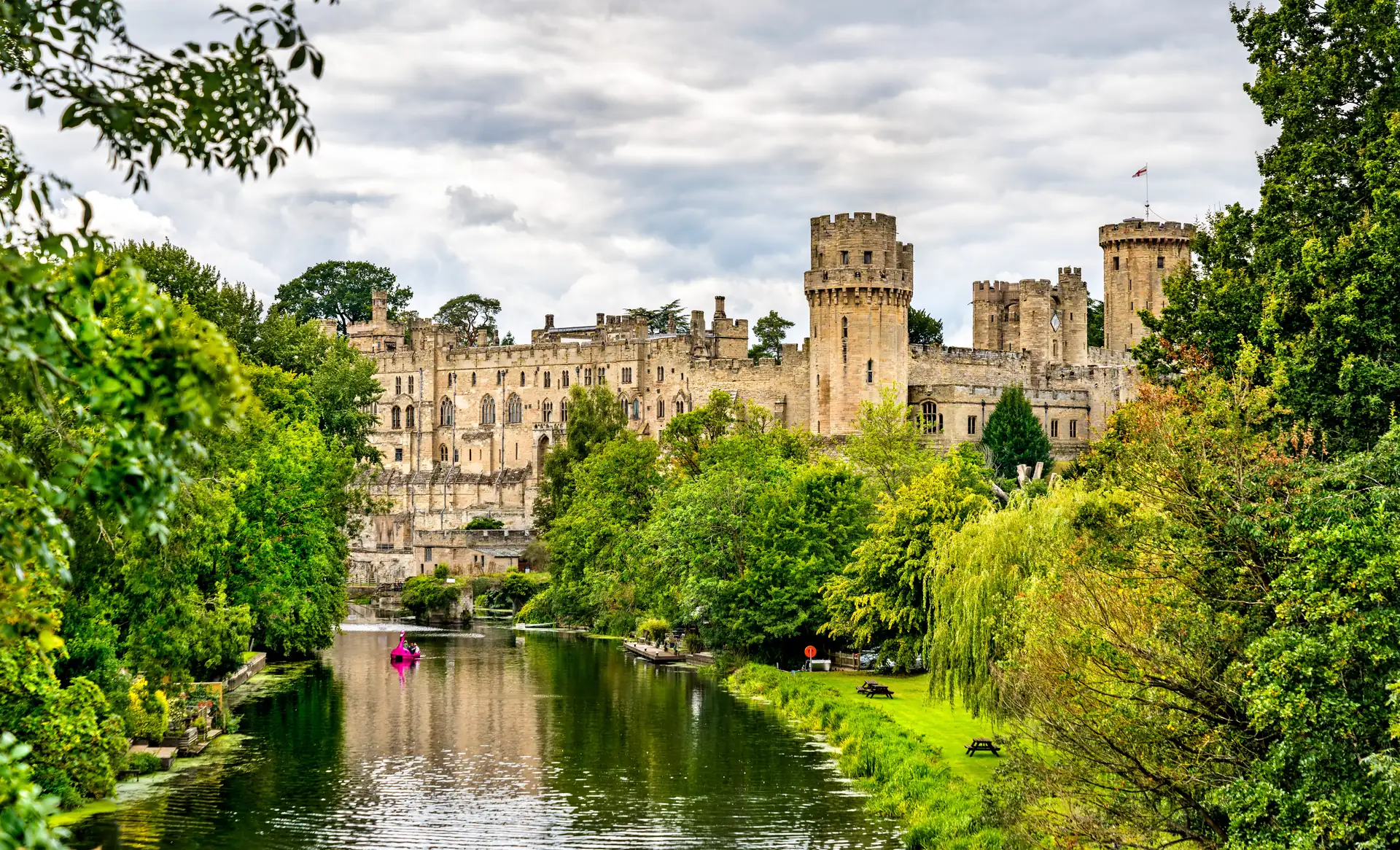 Mittelalterliches Warwick Castle vom Fluss aus mit grünen Ufern.