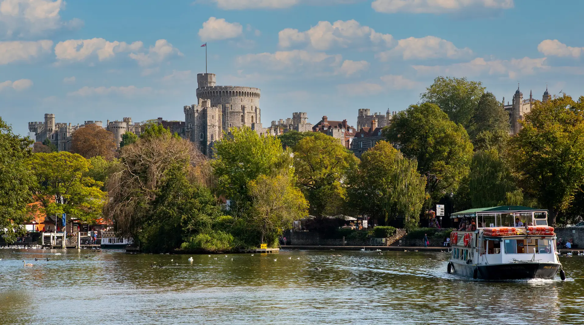 Ein Touristenboot auf der Themse bei Windsor mit Windsor Castle im Hintergrund.