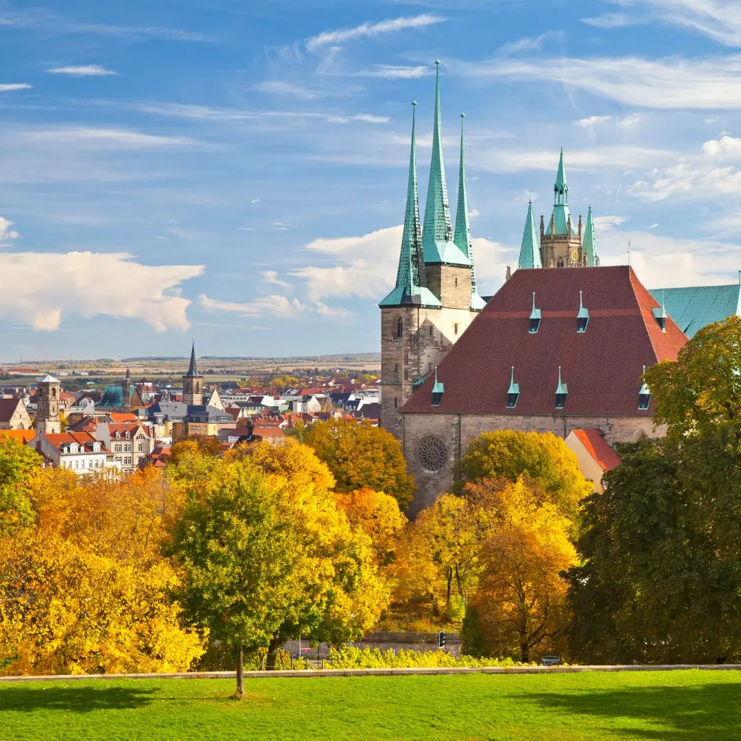 Erfurter Dom vor einer malerischen Herbstlandschaft mit blauen Himmel.