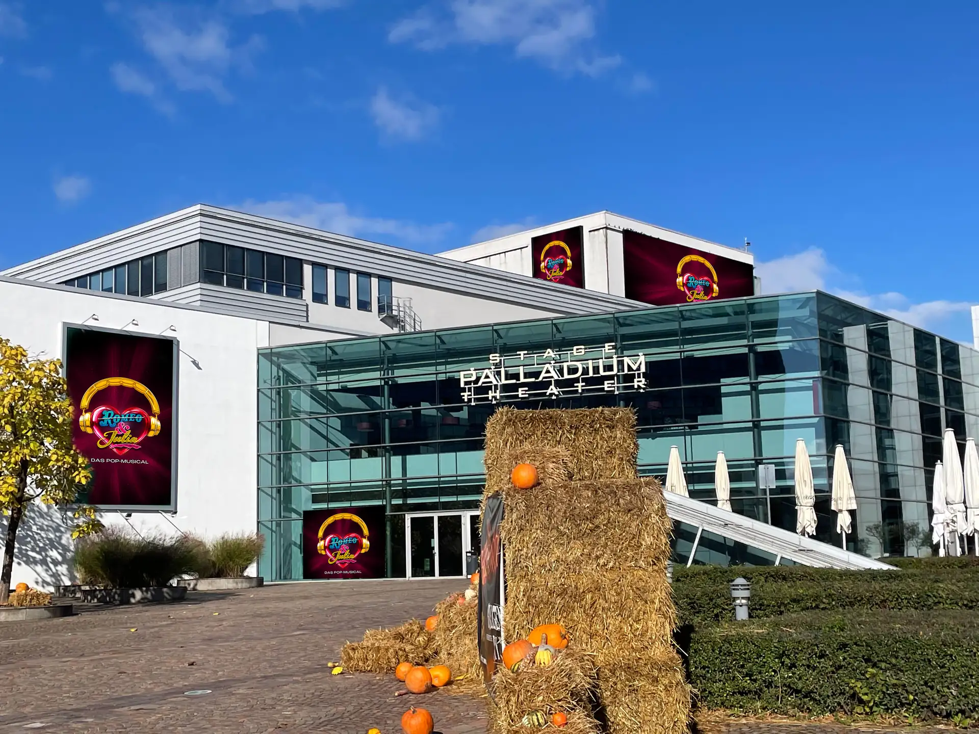 Das moderne Stage Palladium Theater mit Glasfassade zeigt mehrere Plakate für das Musical 