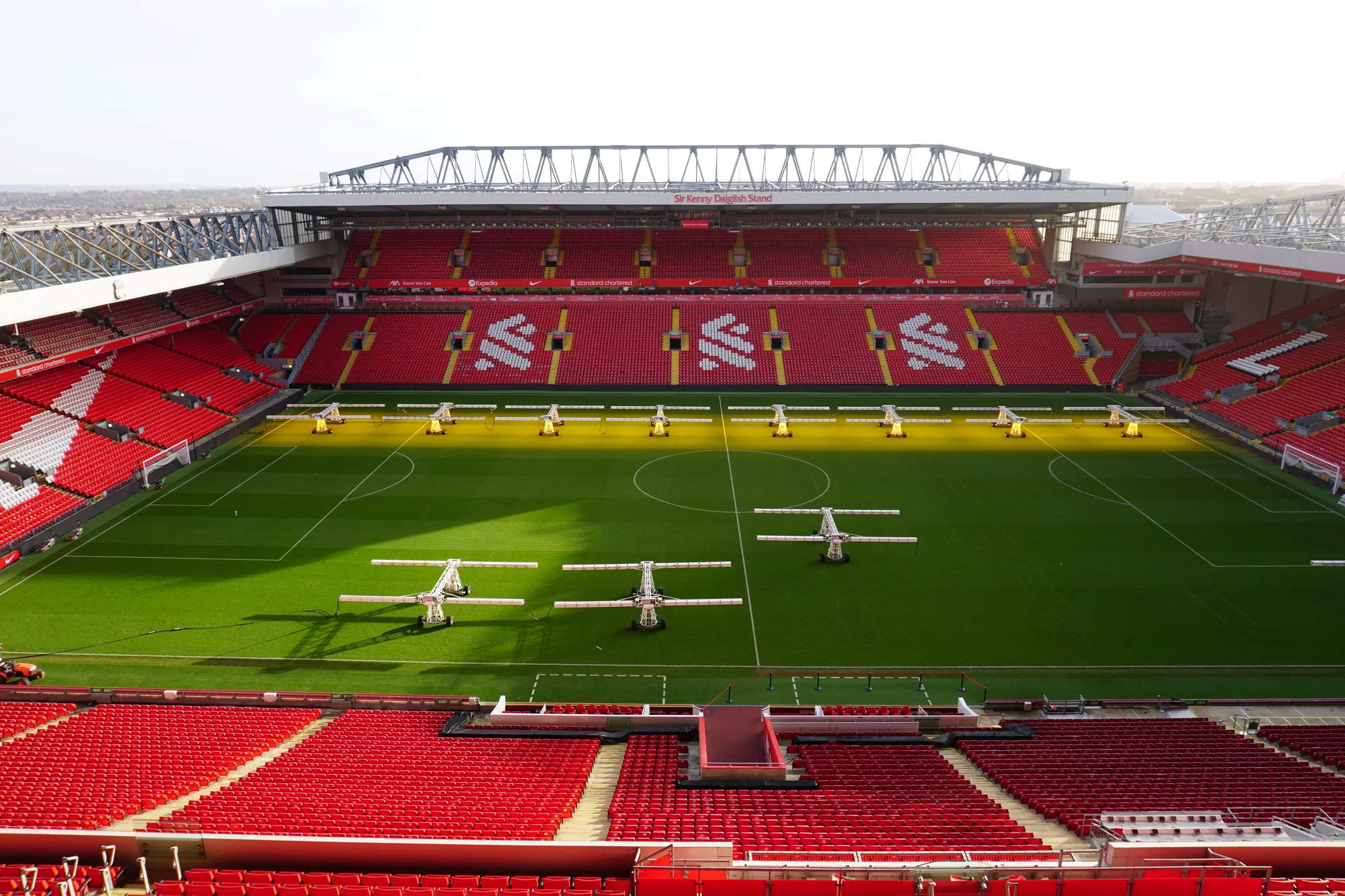 Das Spielfeld des FC Liverpool befindet sich im legendären Anfield-Stadion. Die Aufnahme zeigt das gepflegte Grün, das mit speziellen Lichtanlagen zur Unterstützung des Wachstums ausgestattet ist. Die roten Sitze im Stadion sind ein charakteristisches Merkmal und reflektieren die Vereinsfarben. Anfield ist bekannt für seine leidenschaftlichen Fans und die einzigartige Atmosphäre während der Spiele.