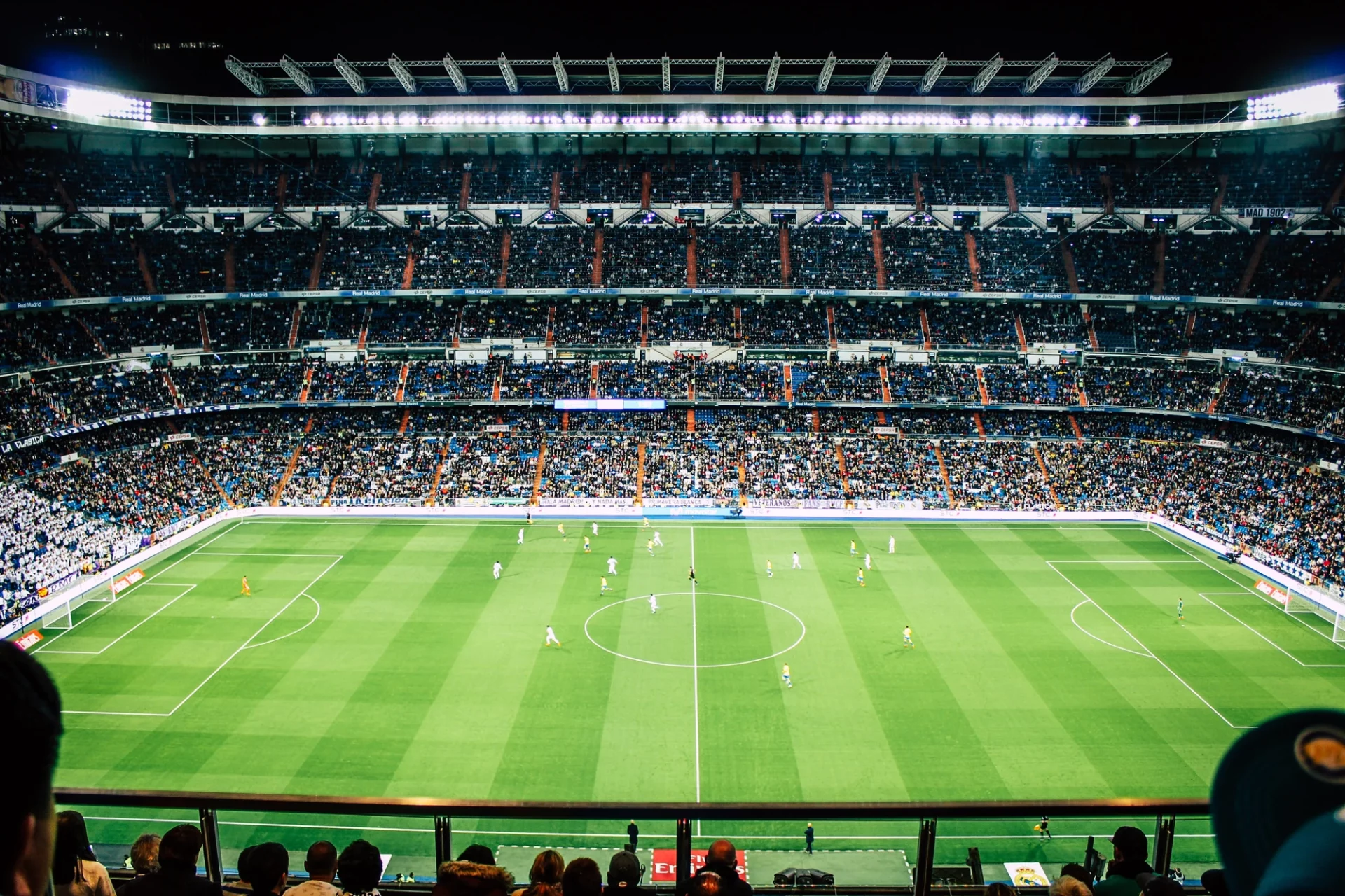 Fußballstadion gut beleuchtet am Abend, Sitzplätze voll, Aussicht auf das grüne Fußballfeld