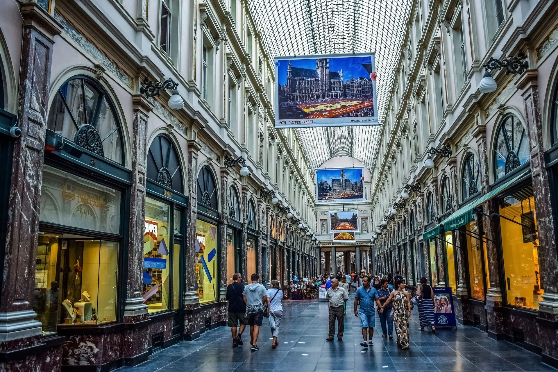 Das Innere der Galeries Royales Saint-Hubert in Brüssel. Unter dem eleganten Glasdach spazieren Menschen, die in den Geschäften bummeln und die Atmosphäre der historischen Einkaufspassage genießen.