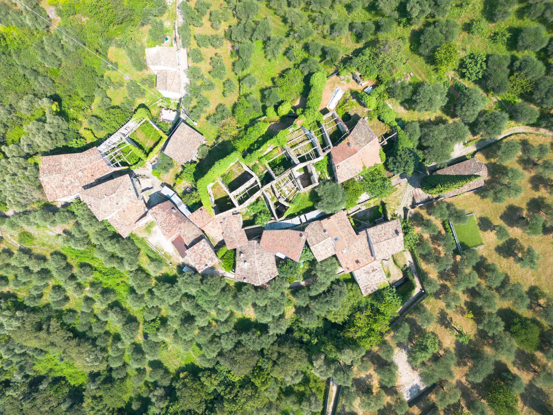 Luftaufnahme des verlassenen Ortes Campo di Brenzone mit alten Gebäuden und umgebenden Bäumen