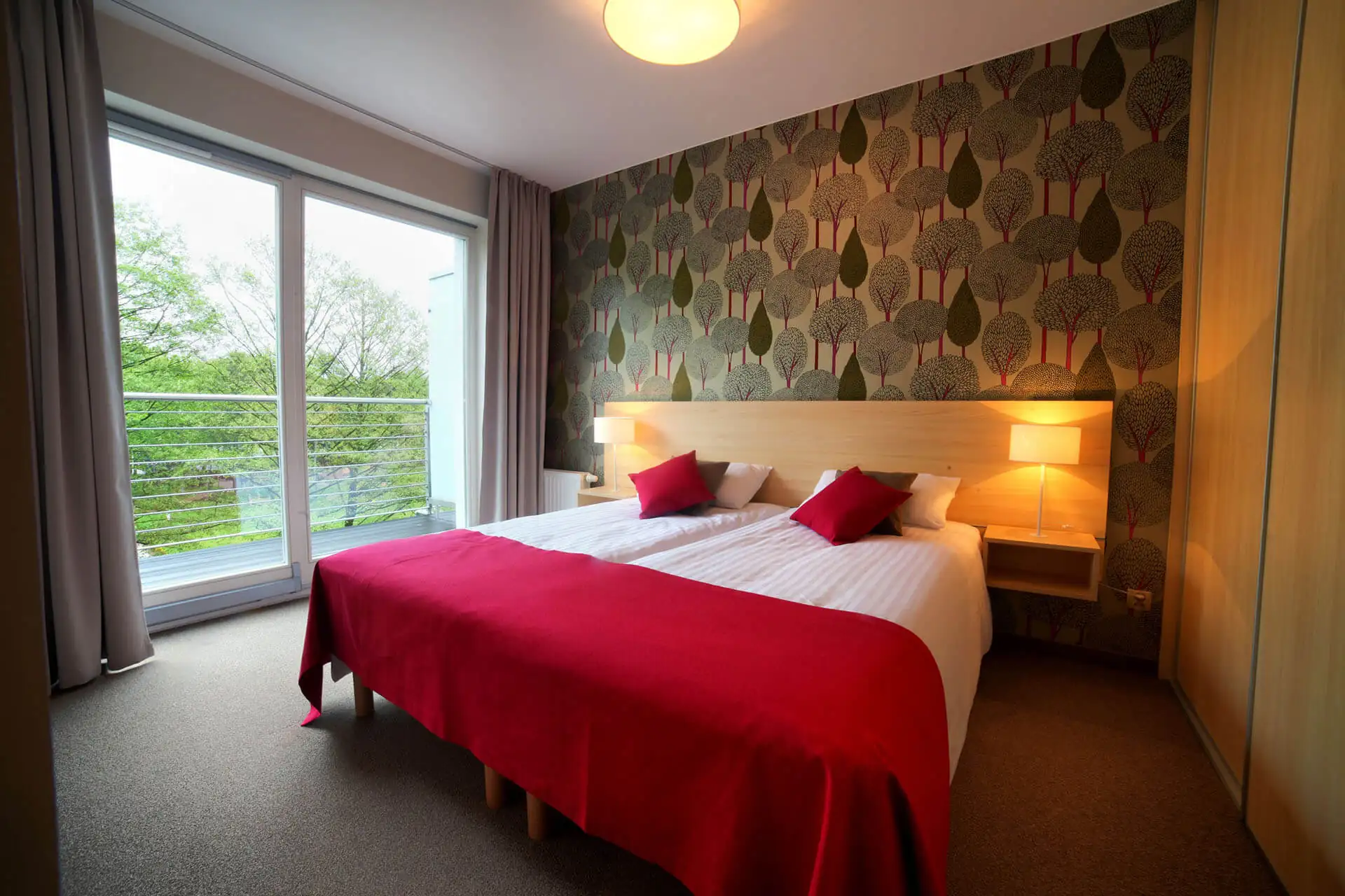 Blick auf das Schlafzimmer mit Doppelbett und großem bodentiefen Fenster / Balkon in der Apartment Suite im Golden Tulip Miedzyzdroje Residence