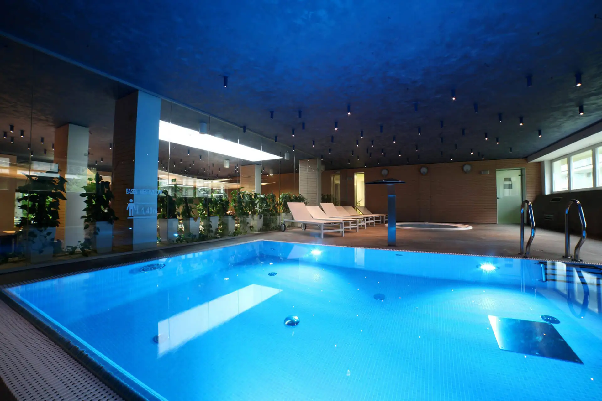 Indoor-Pool im Golden Tulip Miedzyzdroje Residence mit weißen Liegen im Hintergrund