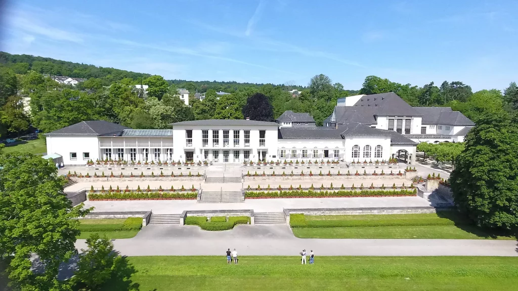 Golfarrangements - Blick auf das Wellnesshotel Dolce Bad Nauheim umgeben von einer grünen Parkanlage mit terrassenförmigen Aufgang