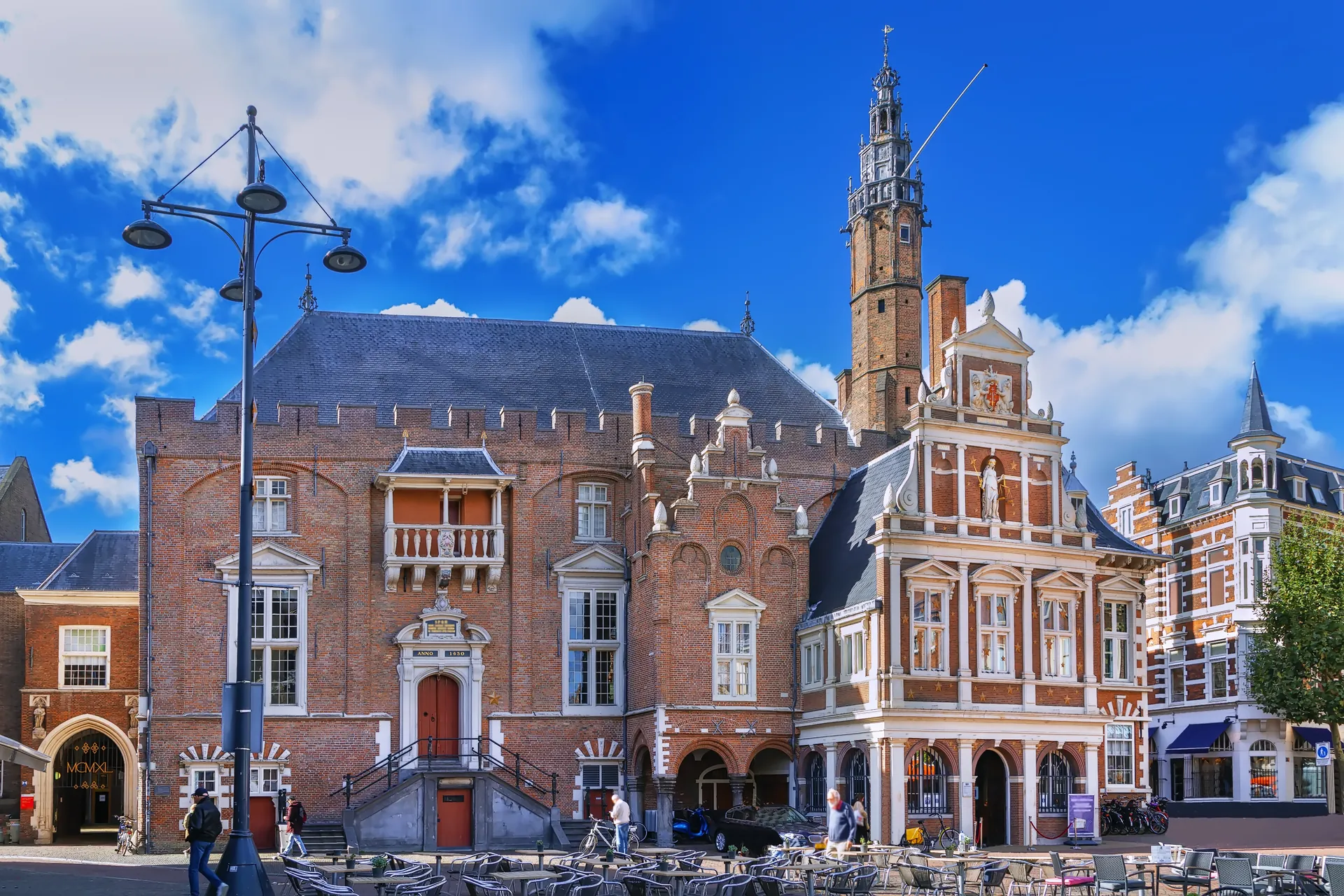 Das historische Rathaus von Haarlem, strahlend im Sonnenlicht. Die beeindruckende Fassade und die architektonischen Details des Gebäudes kommen bei diesem schönen Wetter besonders zur Geltung. Die warme Beleuchtung vermittelt eine einladende Atmosphäre und unterstreicht die Bedeutung dieses historischen Wahrzeichens der Stadt.