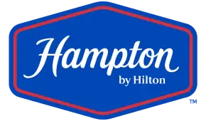 Logo von Hampton by Hilton mit weißem Schriftzug in einem sechseckigen Rahmen