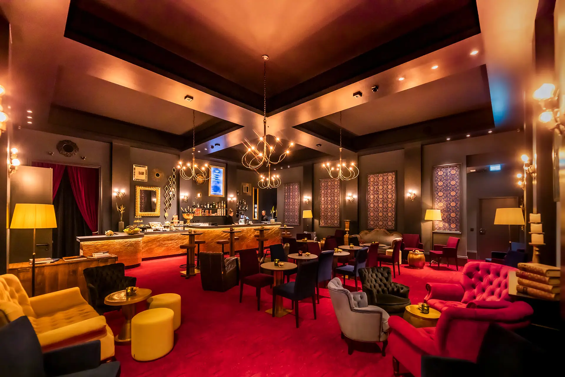 Harry Potter und das verwunschene Kind in Hamburg: Lounge mit gemütlichen Sitzmöglichkeiten, Kronleuchtern und Barbereich.