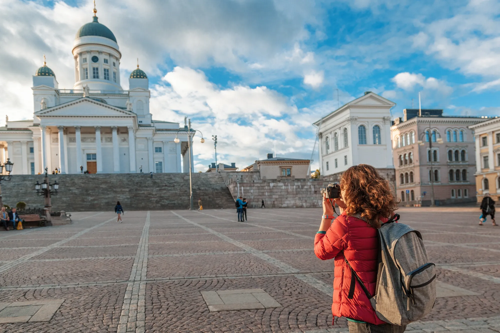 Touristin steht auf dem Senatsplatz und macht ein Foto von der Kathedrale von Helsinki, während die beeindruckende Architektur im Hintergrund erstrahlt.
