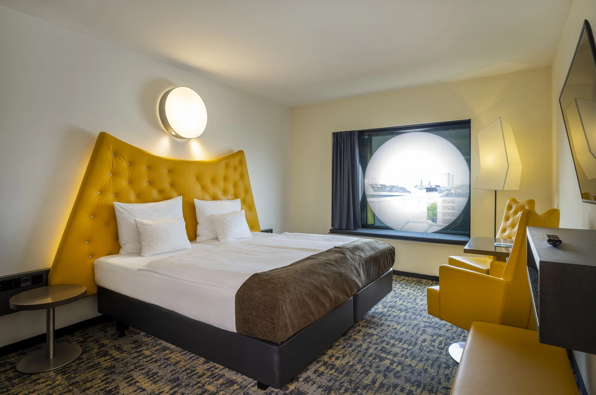 Doppelzimmer im ARCOTEL Onyx Hamburg mit Doppelbett mit einem gelben Leder-Kopfteil und gelben Sesseln und kleinen Beistelltischen