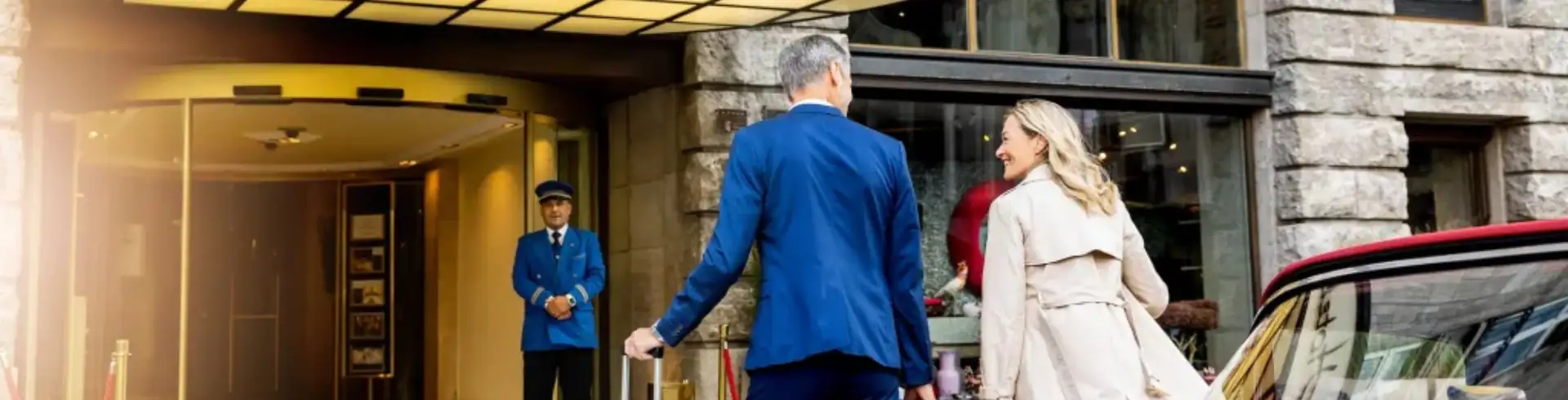 Hotel Legenden im Bannerformat: Paar betritt das luxuriöse Excelsior Hotel Ernst, eines der Hotels in Europa, ein - Doorman erwartet die Gäste.