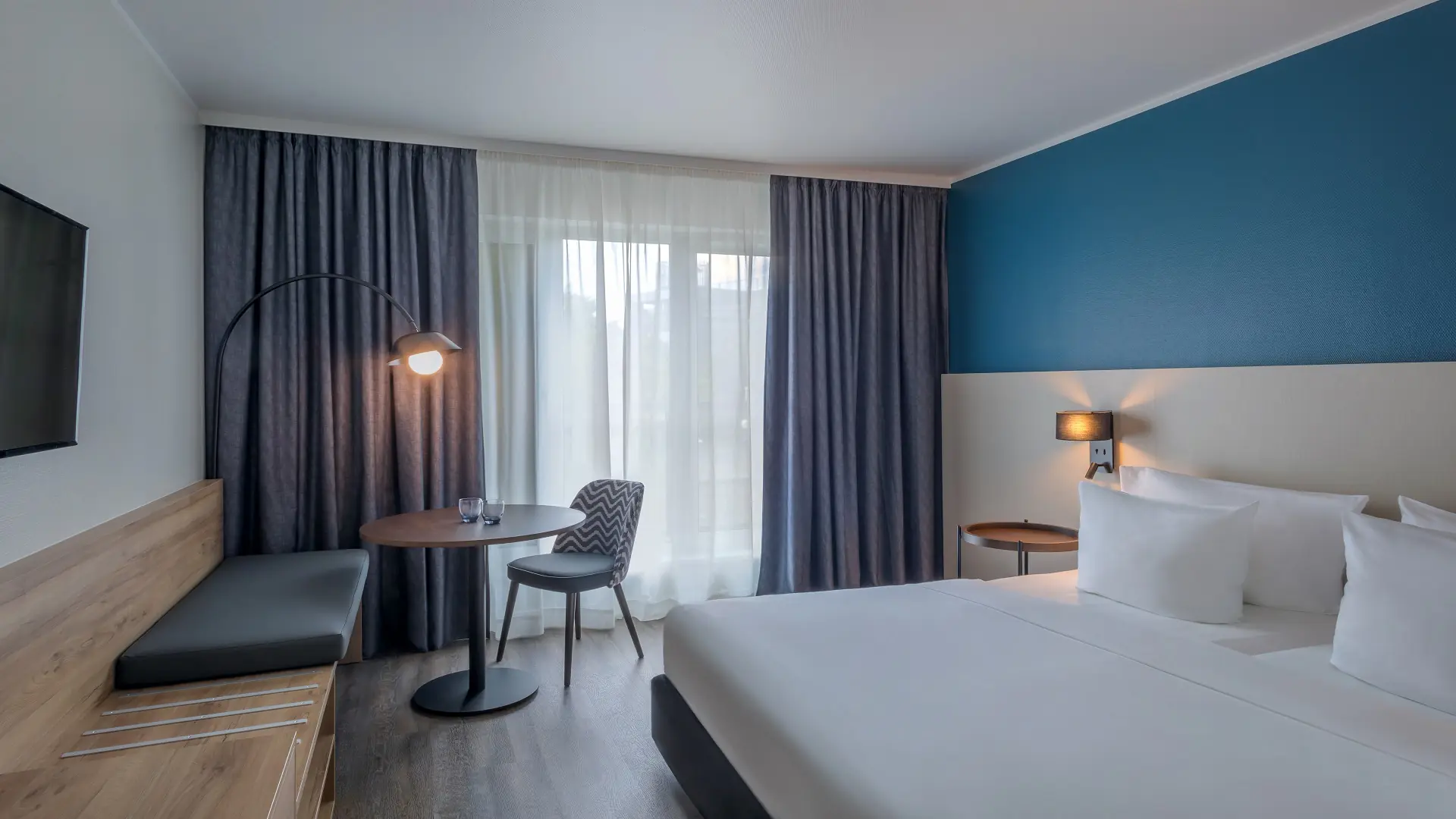 Beispiel für ein Standardzimmer im Hotel Münster Kongresscenter Affiliated by Meliá mit Doppelbett und Sitzgelegenheit