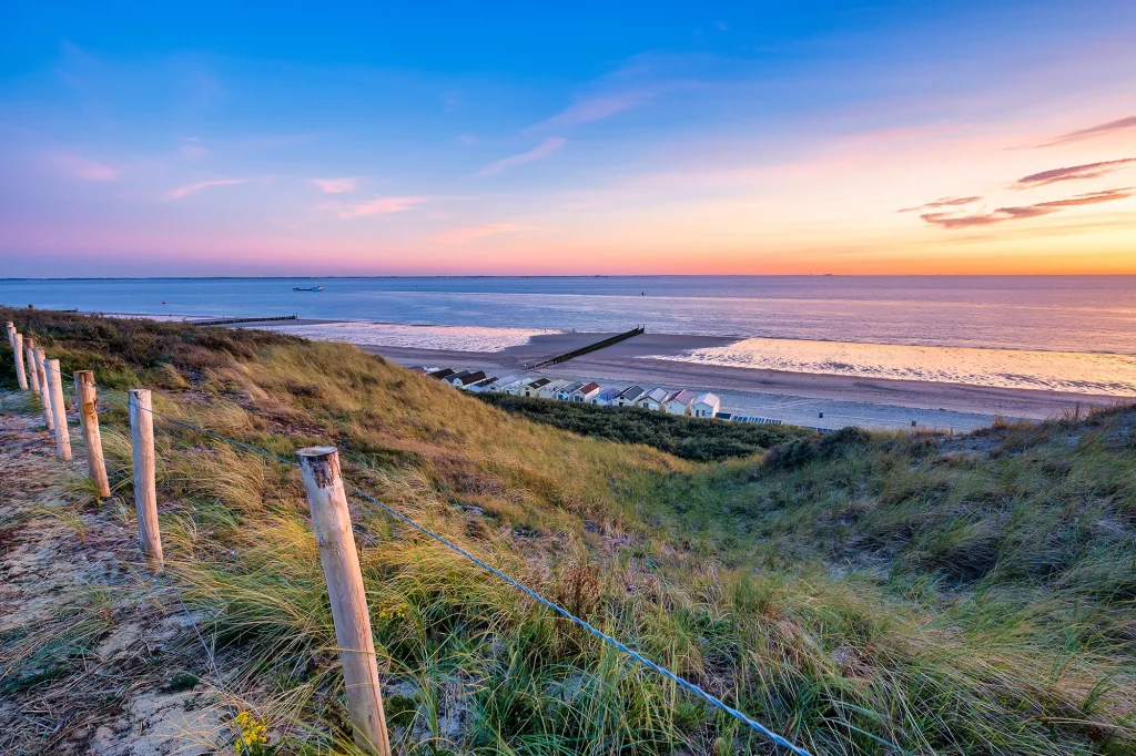 Strandblick mit Strandhäuser aufs Meer im Sonnenuntergang im Urlaub mit Hotels in Zeeland